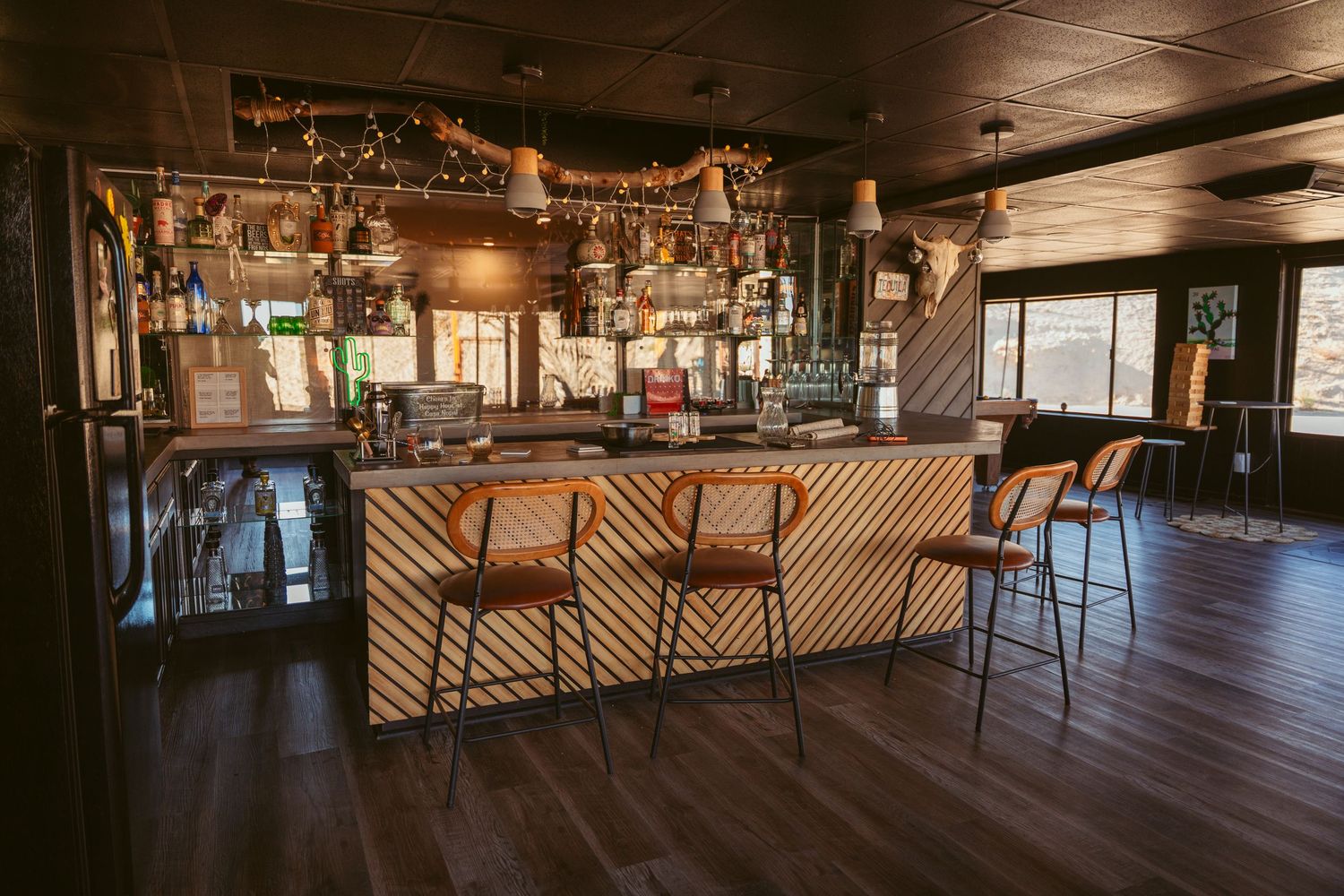 Interior view of an empty rustic bar with wooden floors and ambient lighting.