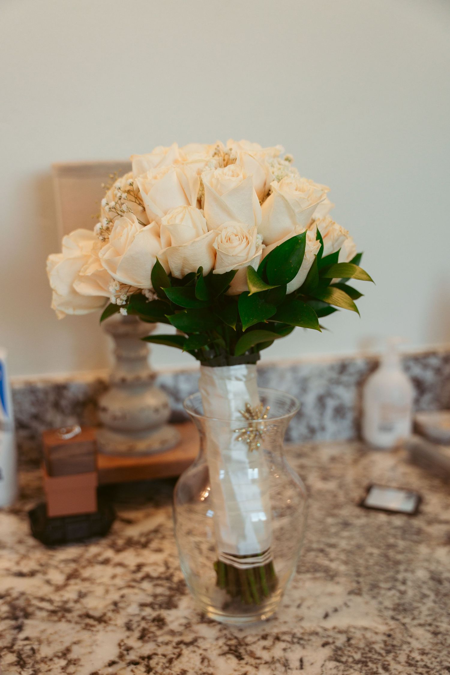 White roses arranged in glass vases on marble countertop.