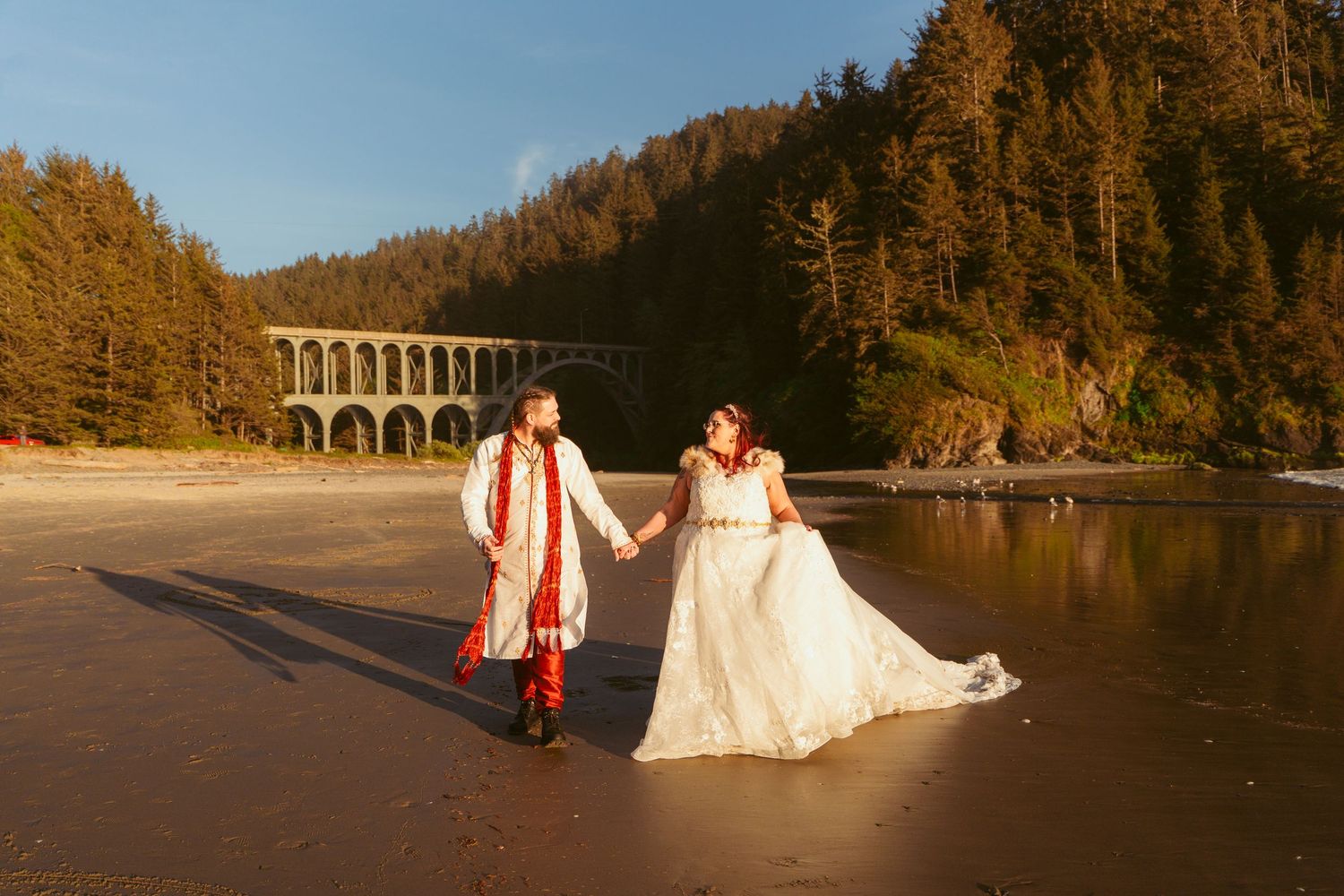 A scenic beach wedding photoshoot with dramatic coastal cliffs and golden sunset lighting.
