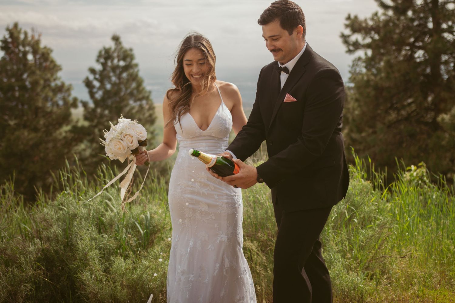 Newlyweds celebrate with champagne during their outdoor mountain wedding ceremony.