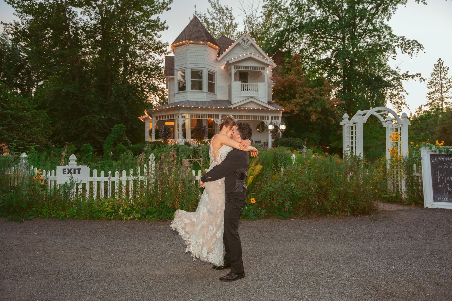 Wedding photo shoot in front of a classic white house with picket fence.