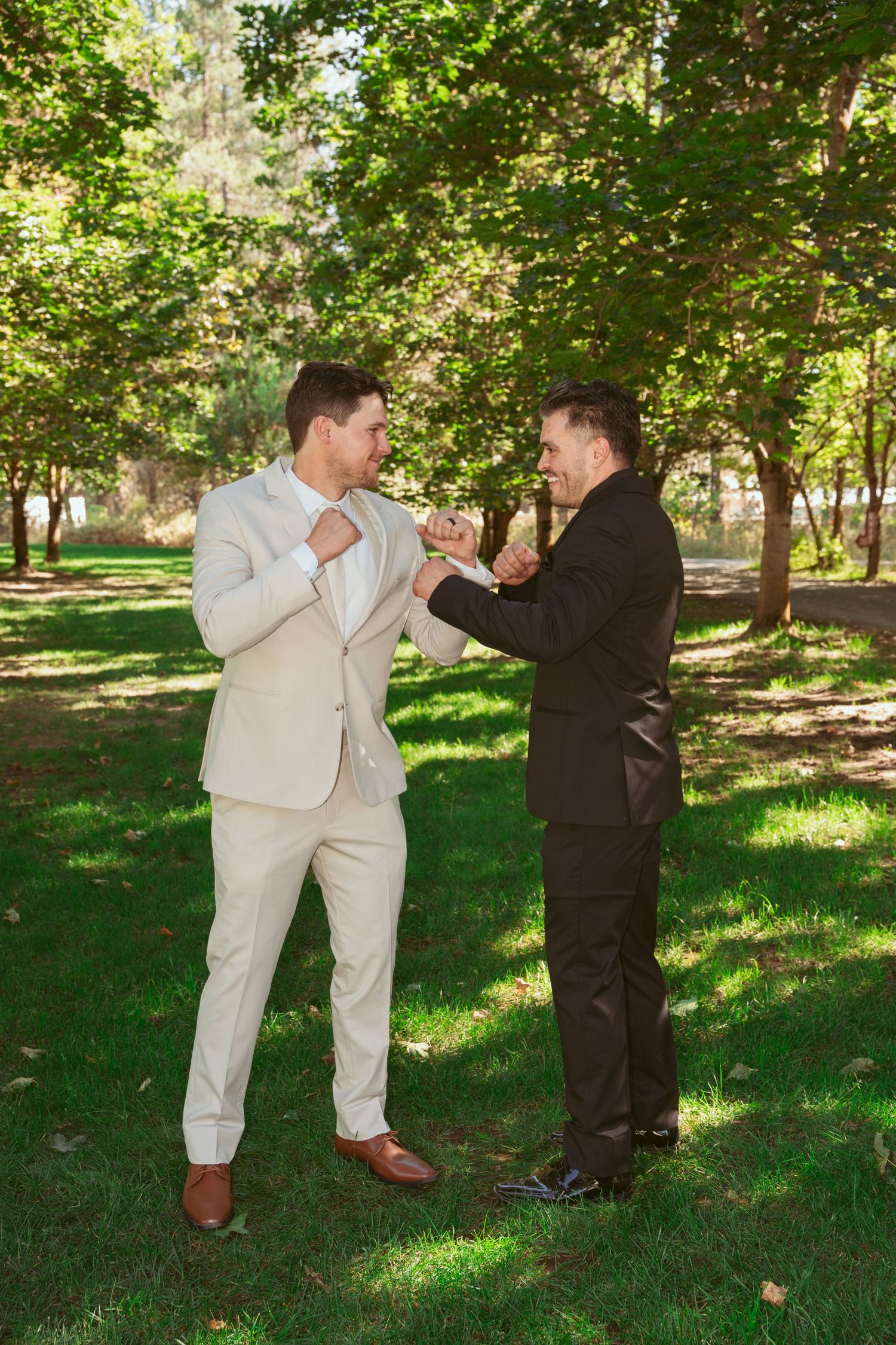 Playful boxing pose between two people in contrasting formal attire outdoors.
