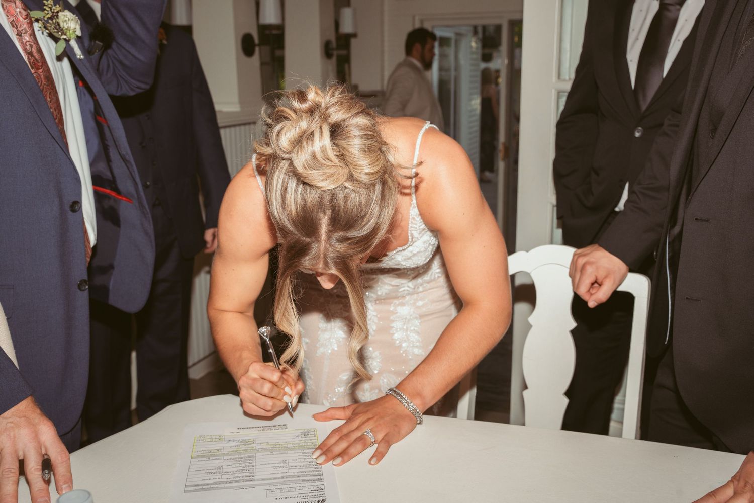 Document signing moment during wedding ceremony with formal attire.
