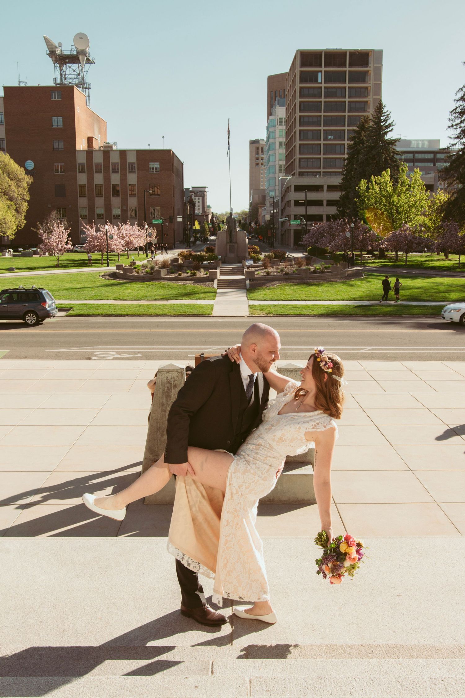 A playful dip pose on an urban plaza with city buildings in the background.