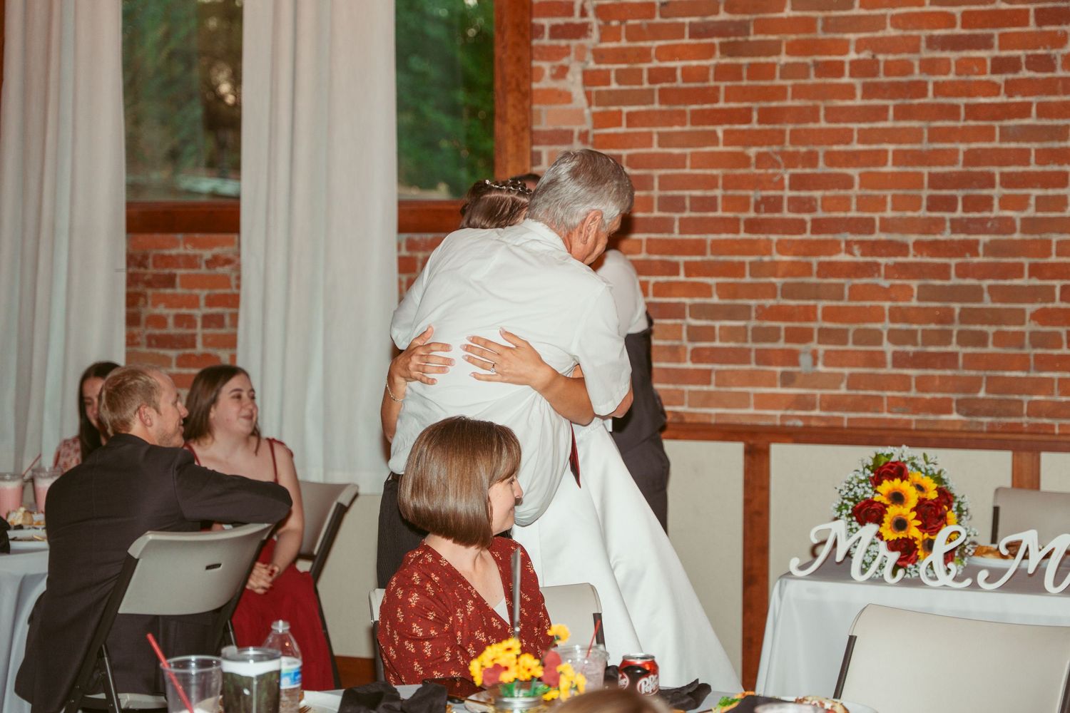 Rustic wedding venue with exposed brick walls and floral centerpieces on tables.