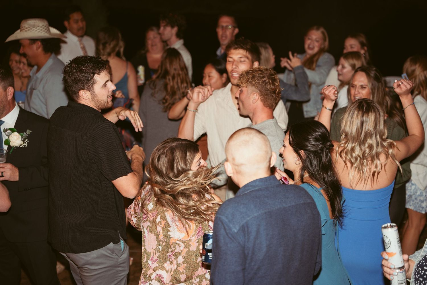 Wedding reception dance floor filled with guests enjoying themselves under evening lighting.