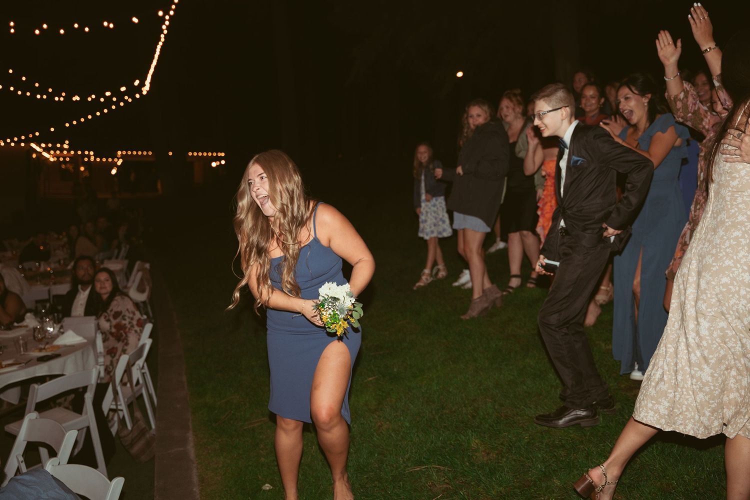 Wedding reception guests enjoying the dance floor under twinkling lights at an outdoor venue.