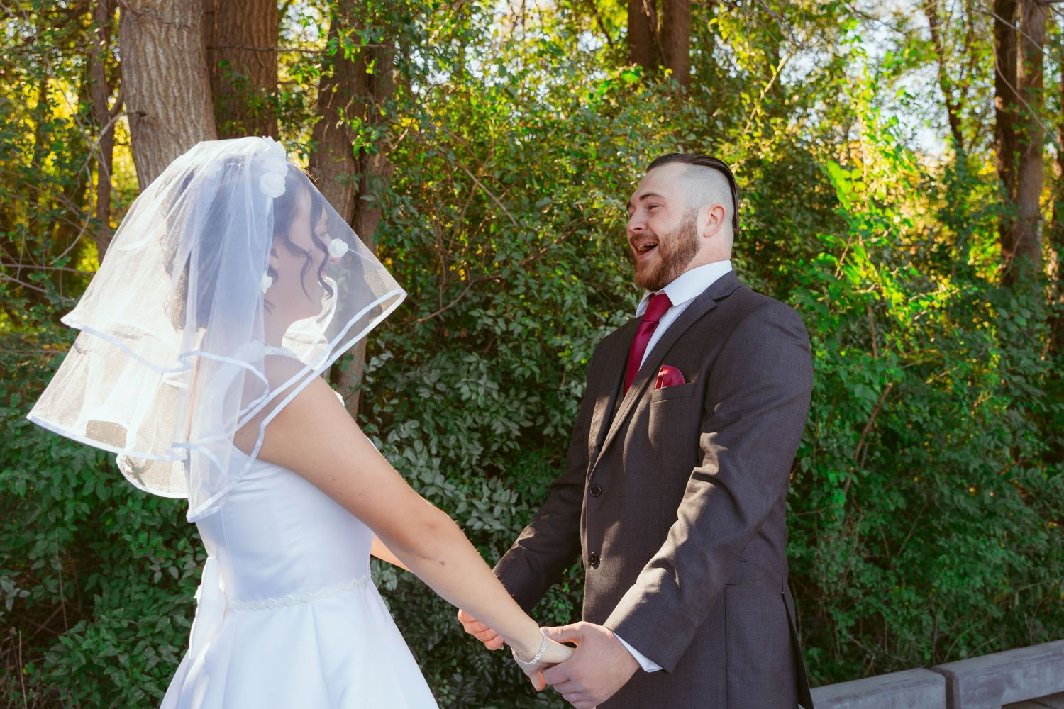 Bride in white dress approaching groom during first look sequence in garden setting.