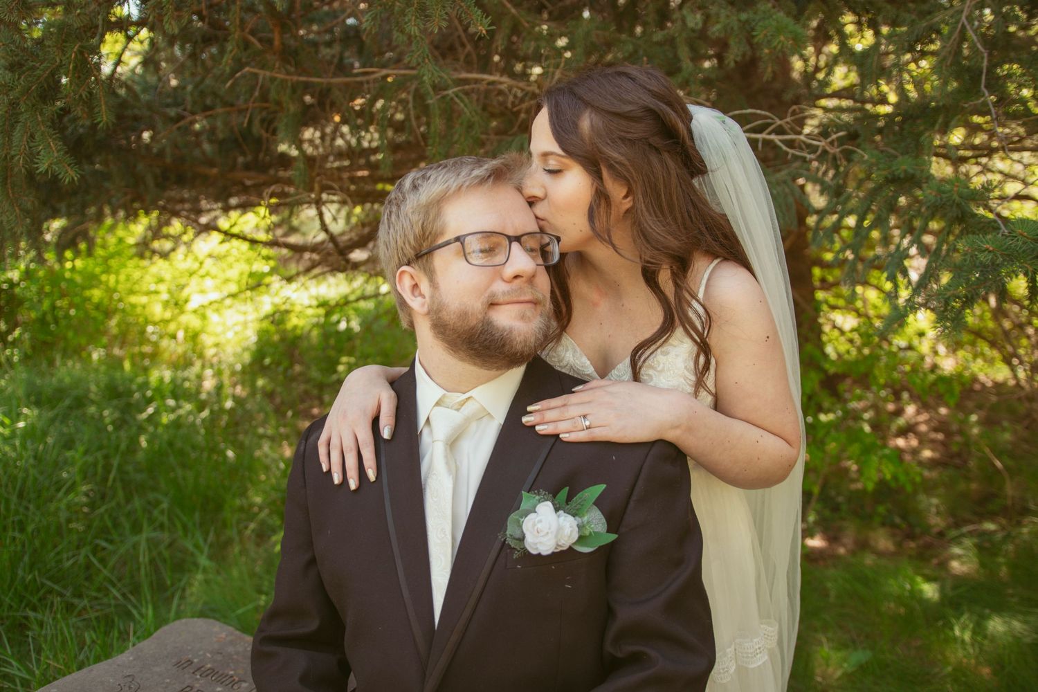 A tender wedding portrait of a couple sharing an intimate moment in a garden setting.