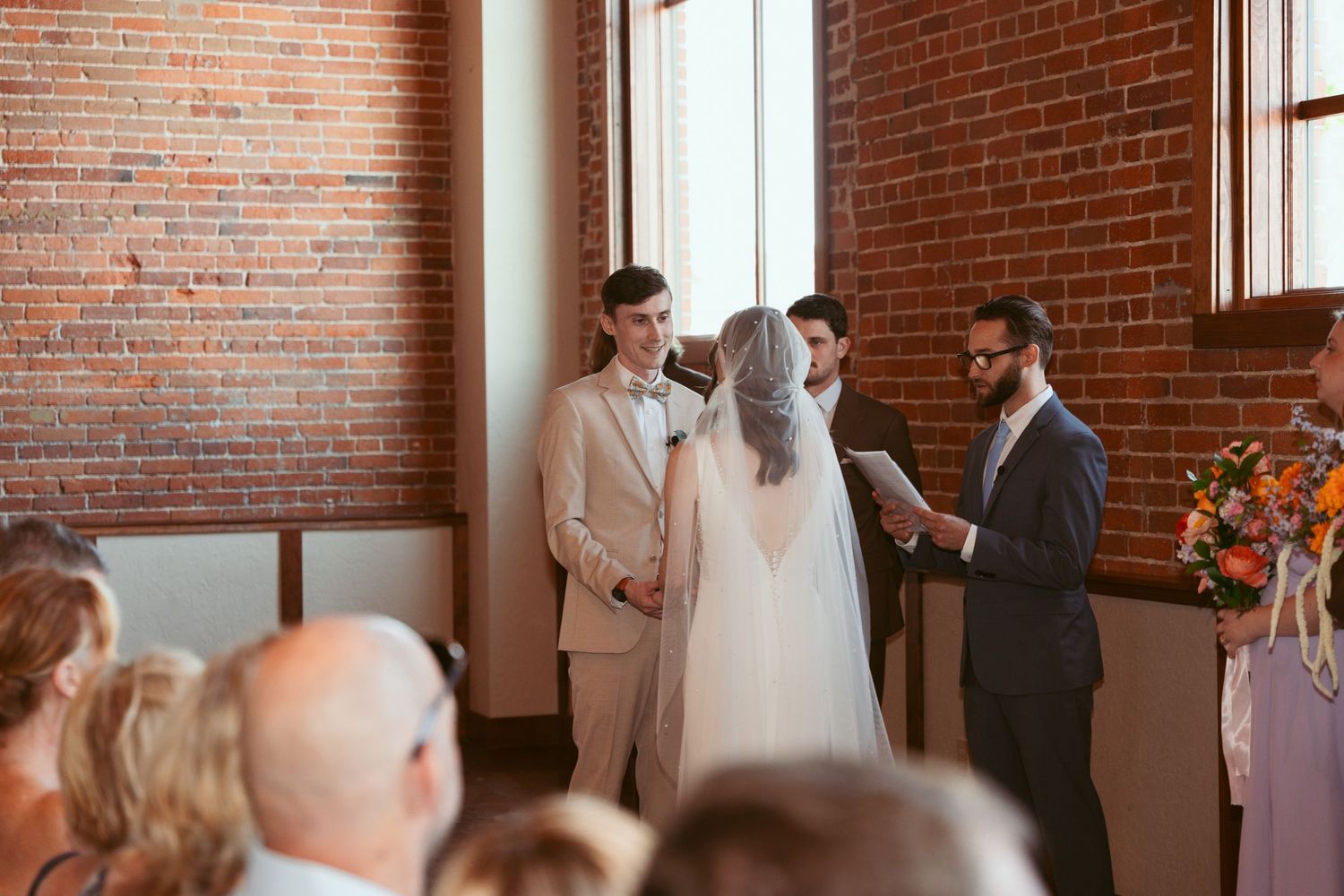 Wedding ceremony in progress at rustic brick venue with natural lighting.