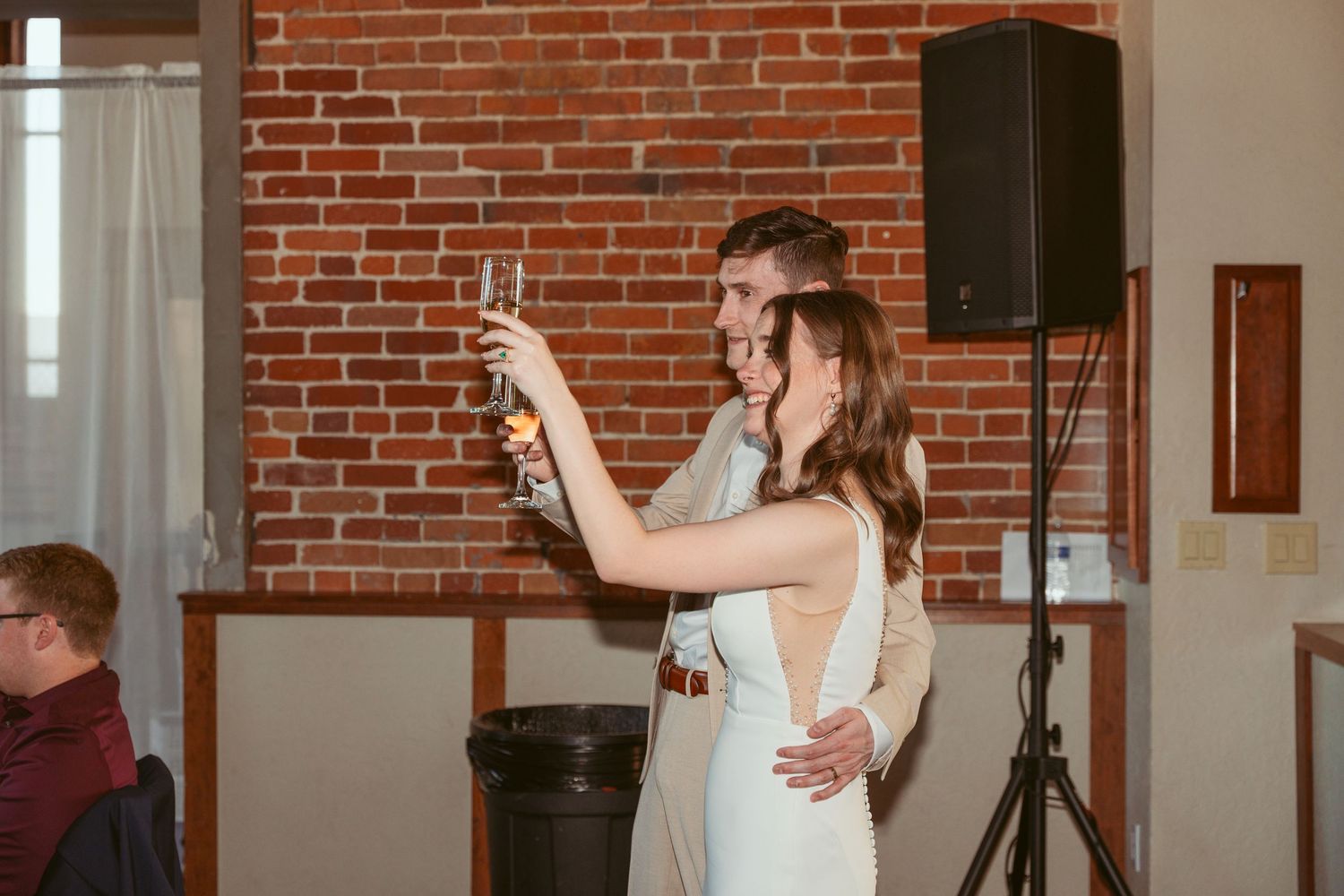 A couple raises their glasses in celebration during their wedding reception.