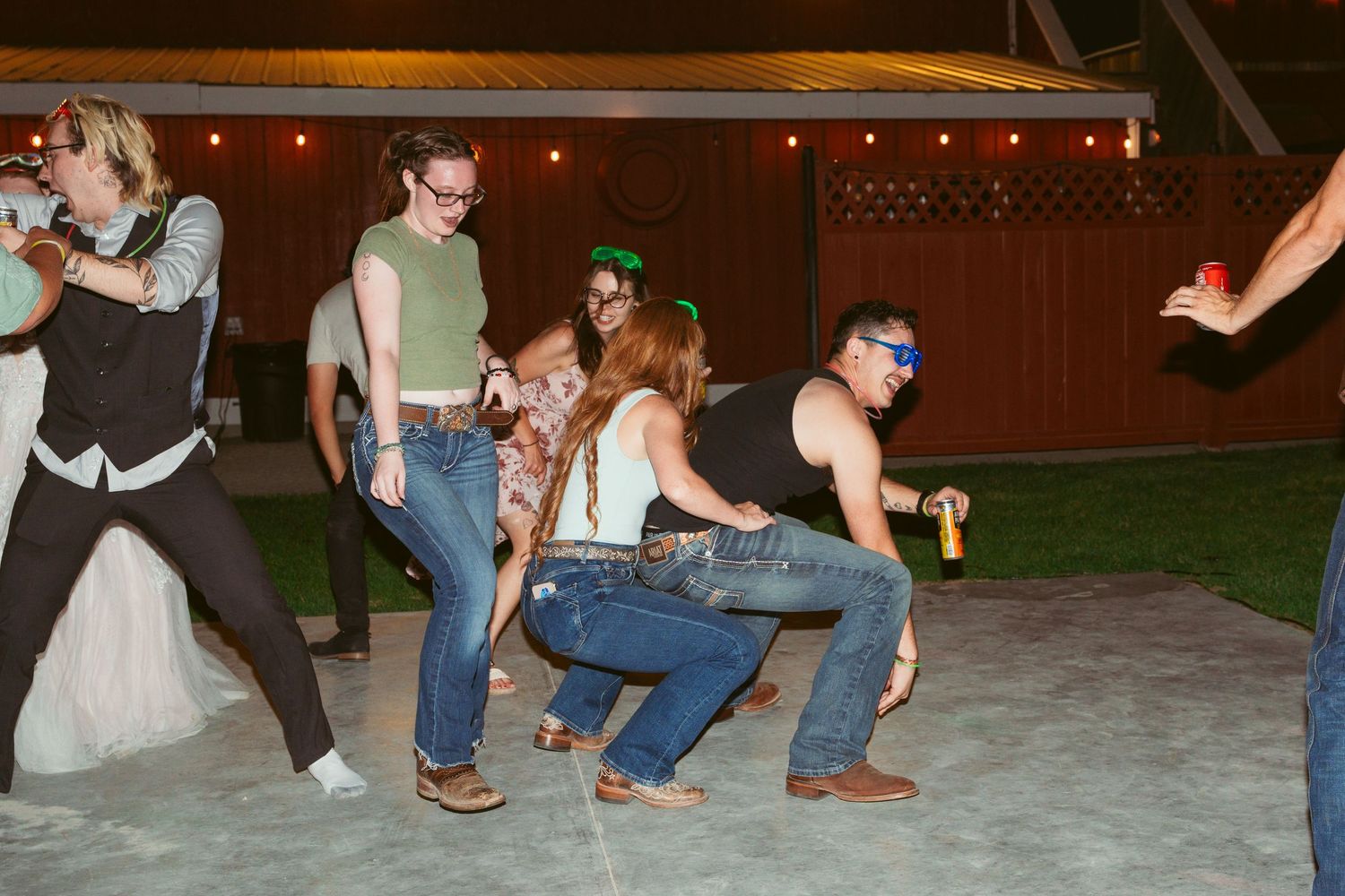 Dancers performing energetic moves on a wooden dance floor at night.