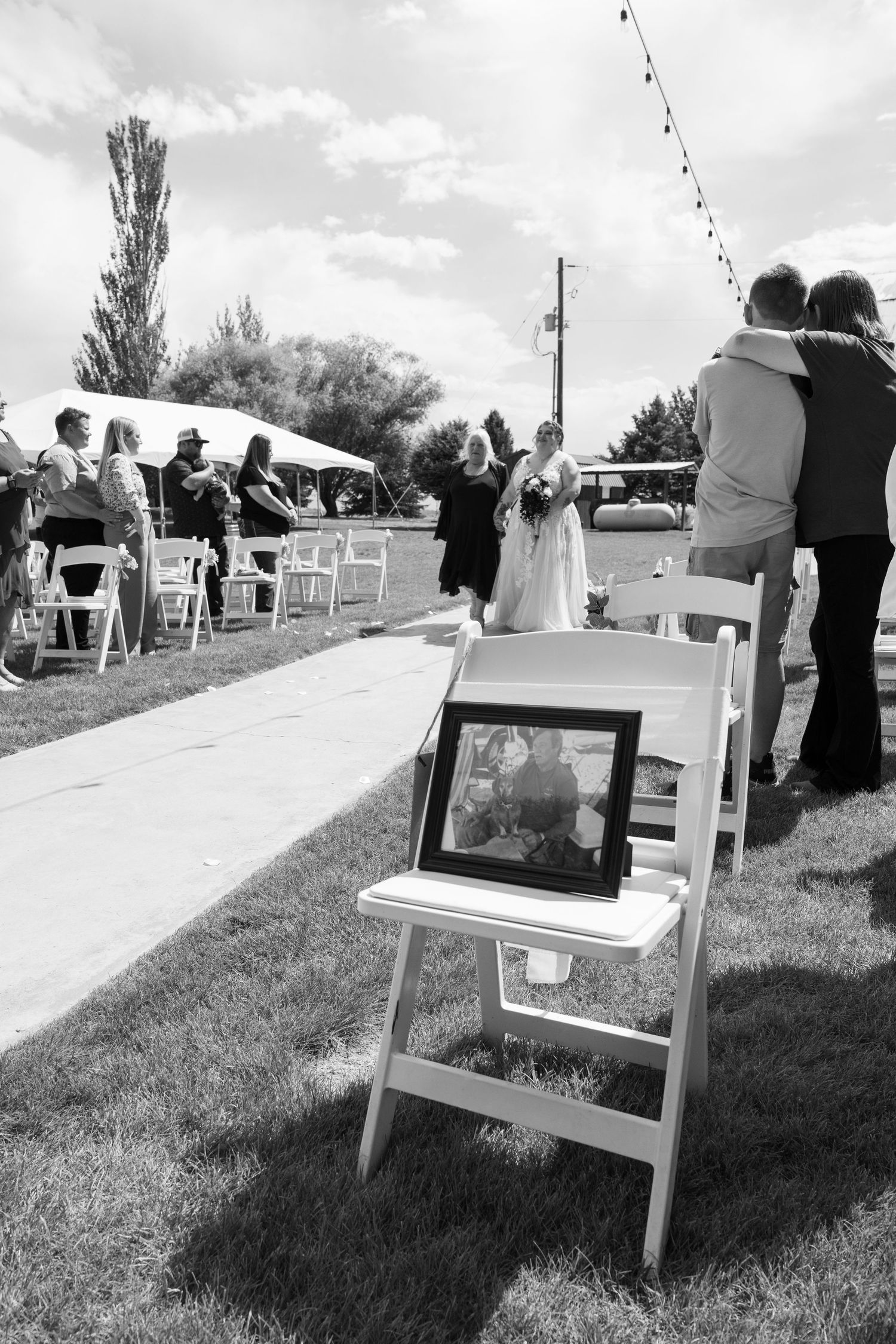 White wooden chairs arranged in rows on a grassy hillside for an outdoor ceremony.