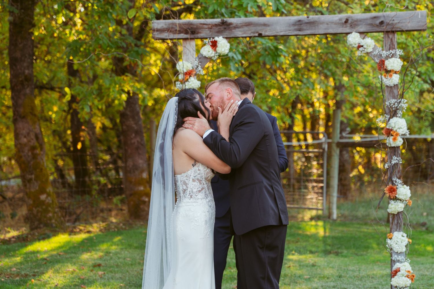 Wedding ceremony taking place at sunset with decorated birch trees and autumn leaves.