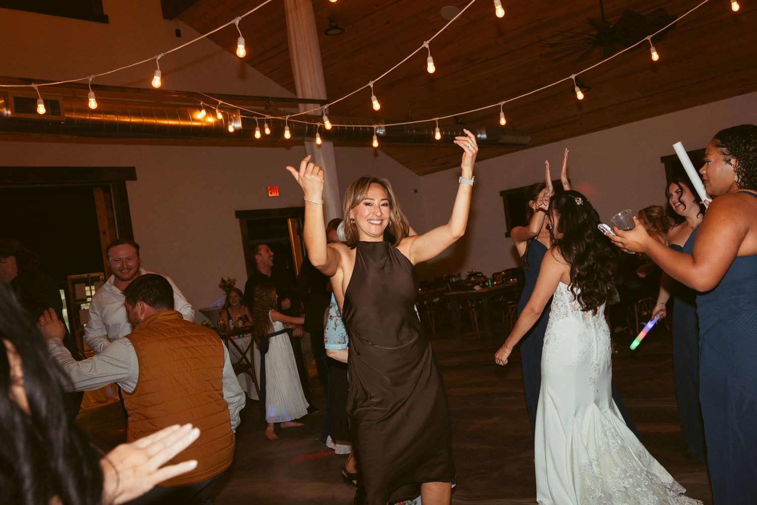 Partygoers dancing and having fun at an indoor reception venue with ambient lighting.