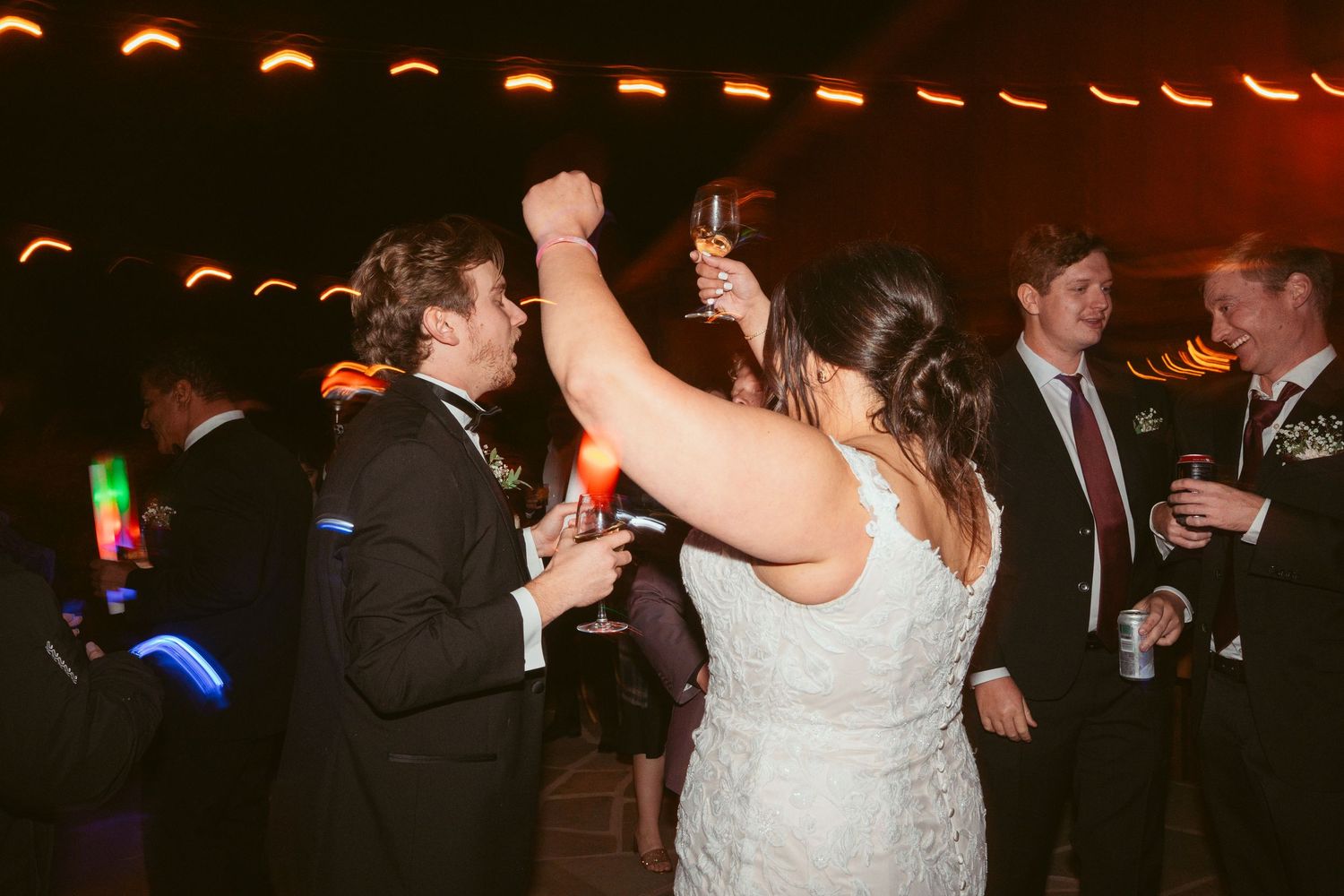 Evening wedding celebration with string lights creating a warm ambiance for dancing guests.