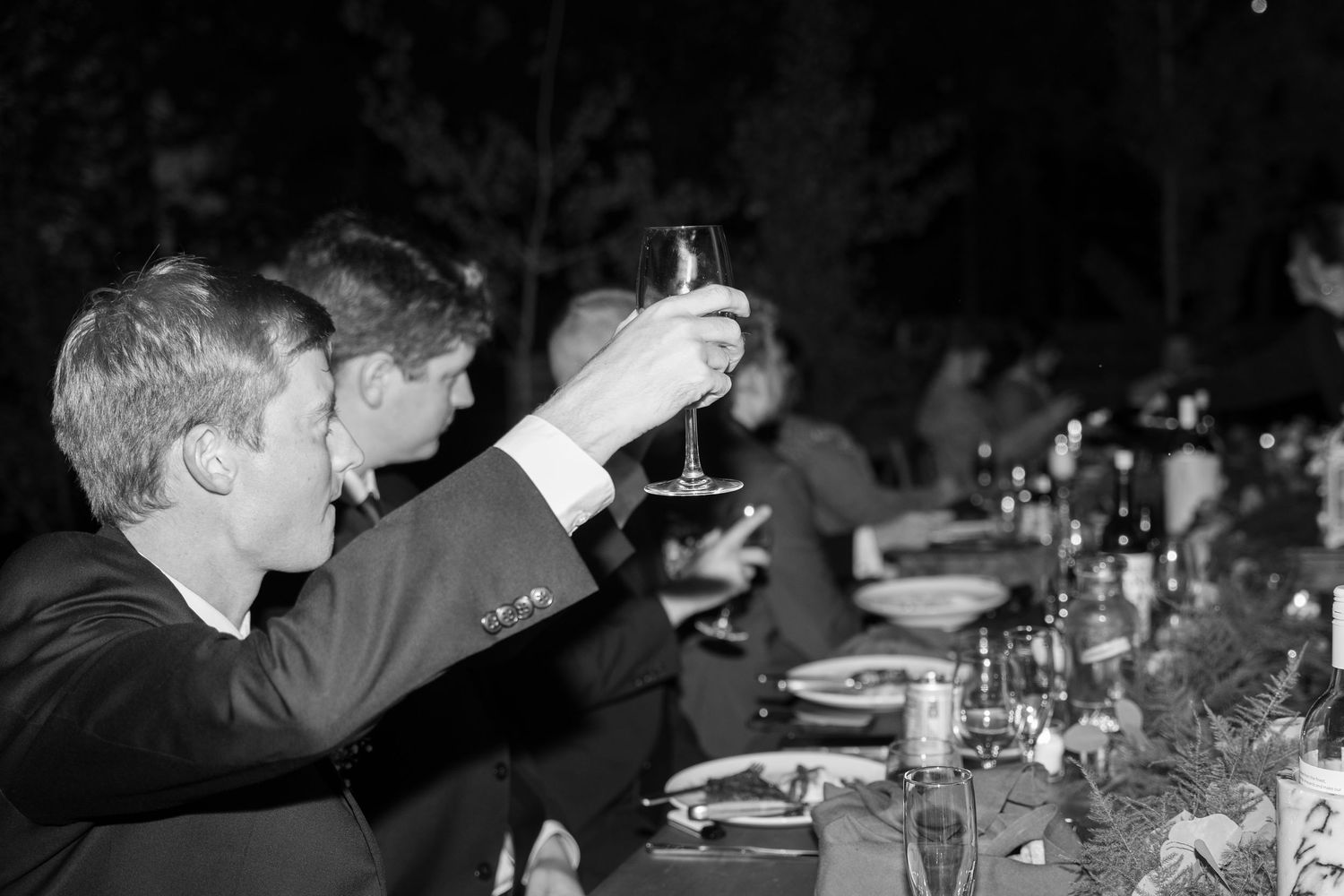 Couple cutting and serving wedding cake at reception in black and white.