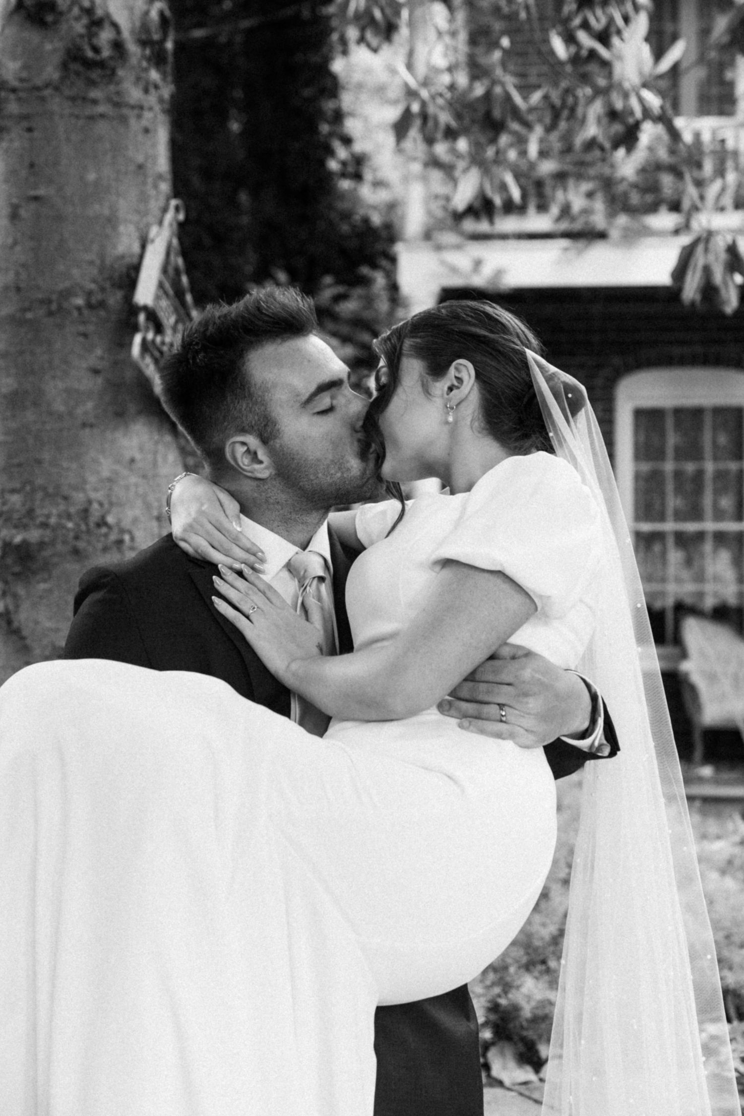 A tender wedding kiss captured in black and white photography.