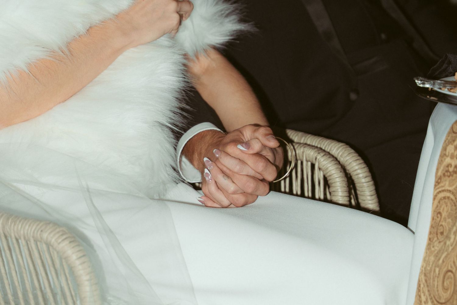 Close-up detail of white wedding dress fabric and formal attire at reception table.