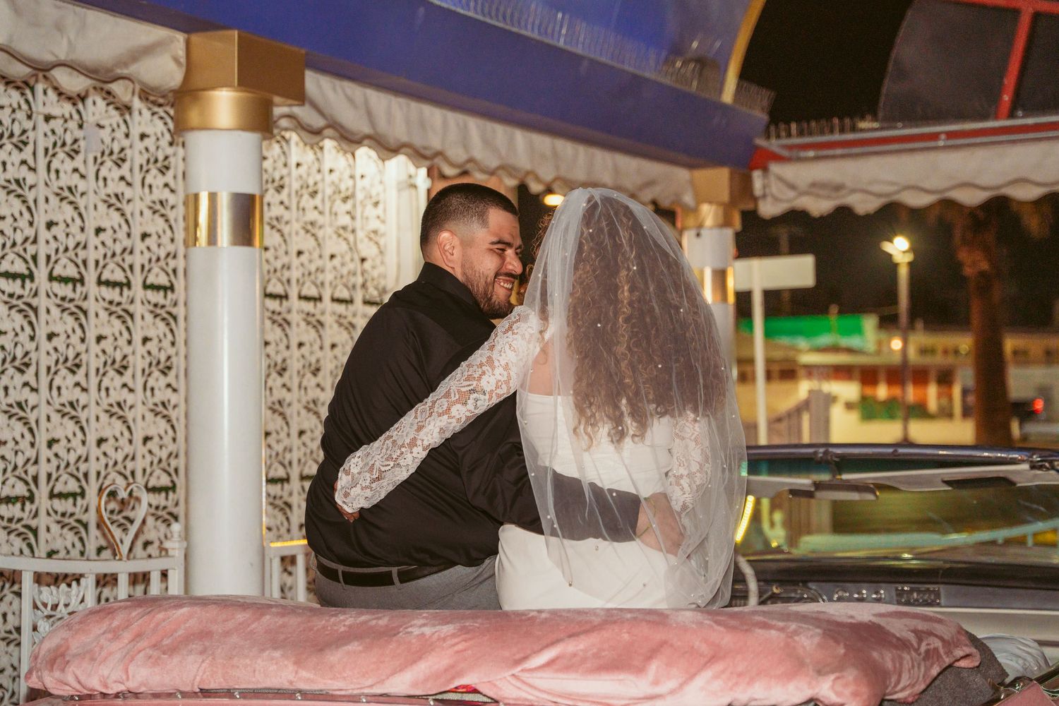 Wedding celebration at night with decorative lights and ornate white architectural details.