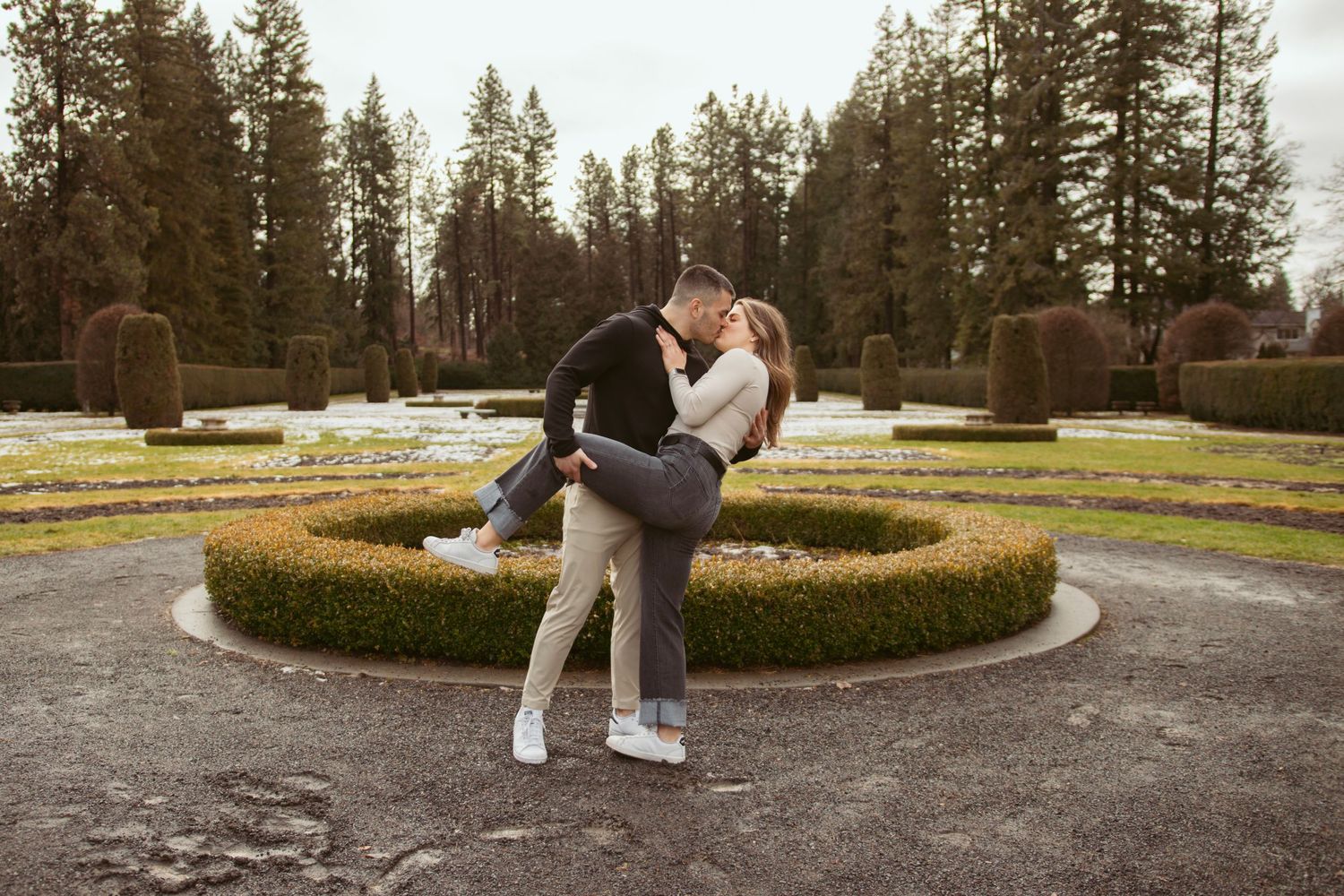 Couple walking and posing in a landscaped garden with circular hedge design.