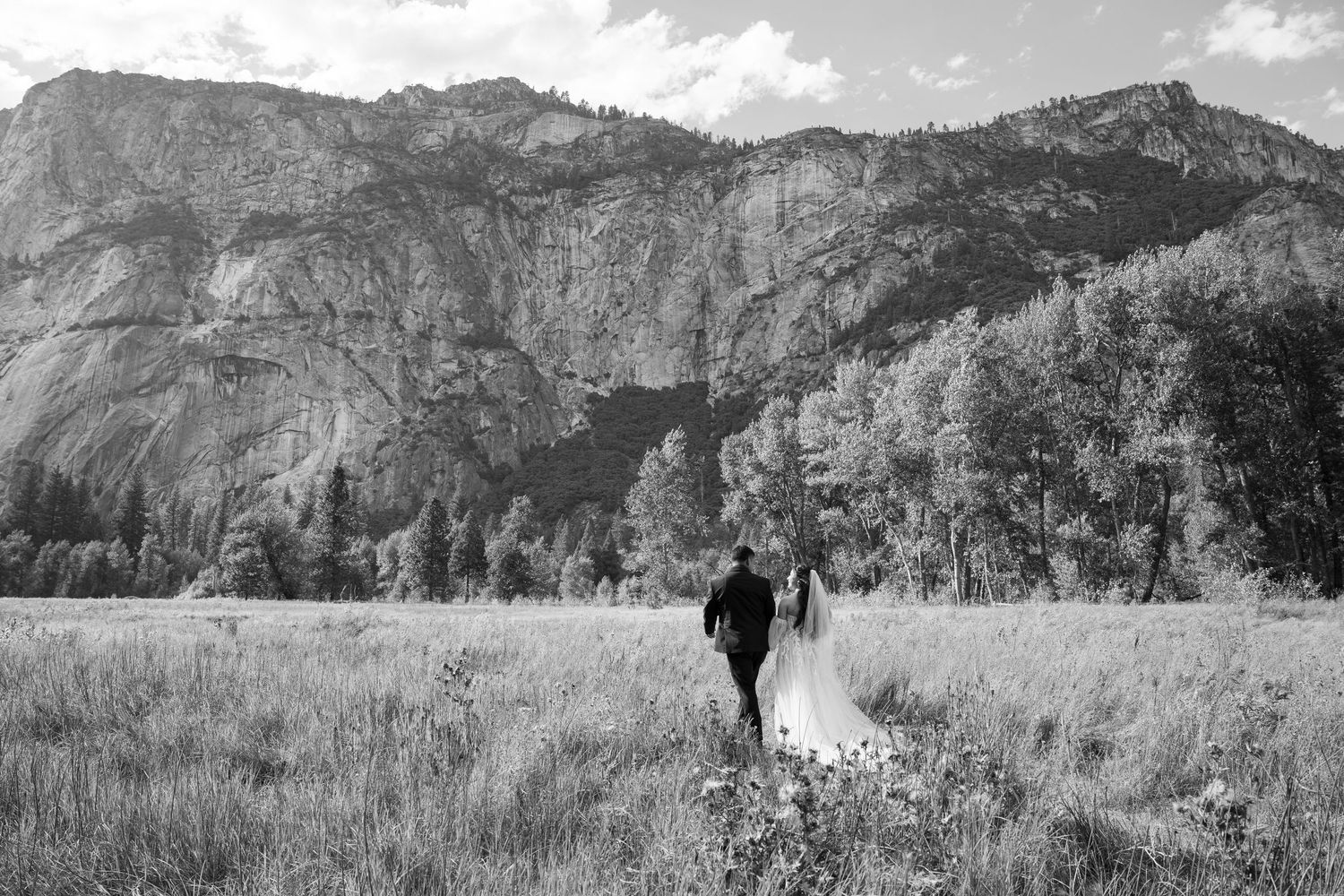 Black and white wedding portrait in Yosemite Valley with dramatic mountain backdrop.