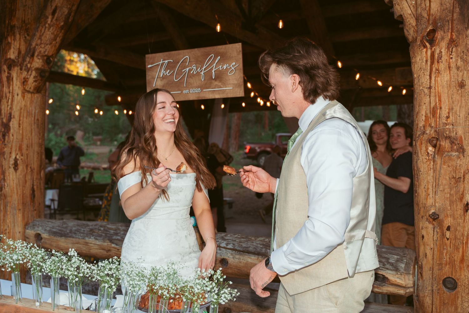 Intimate wedding celebration inside a beautifully lit rustic barn with wooden post details.