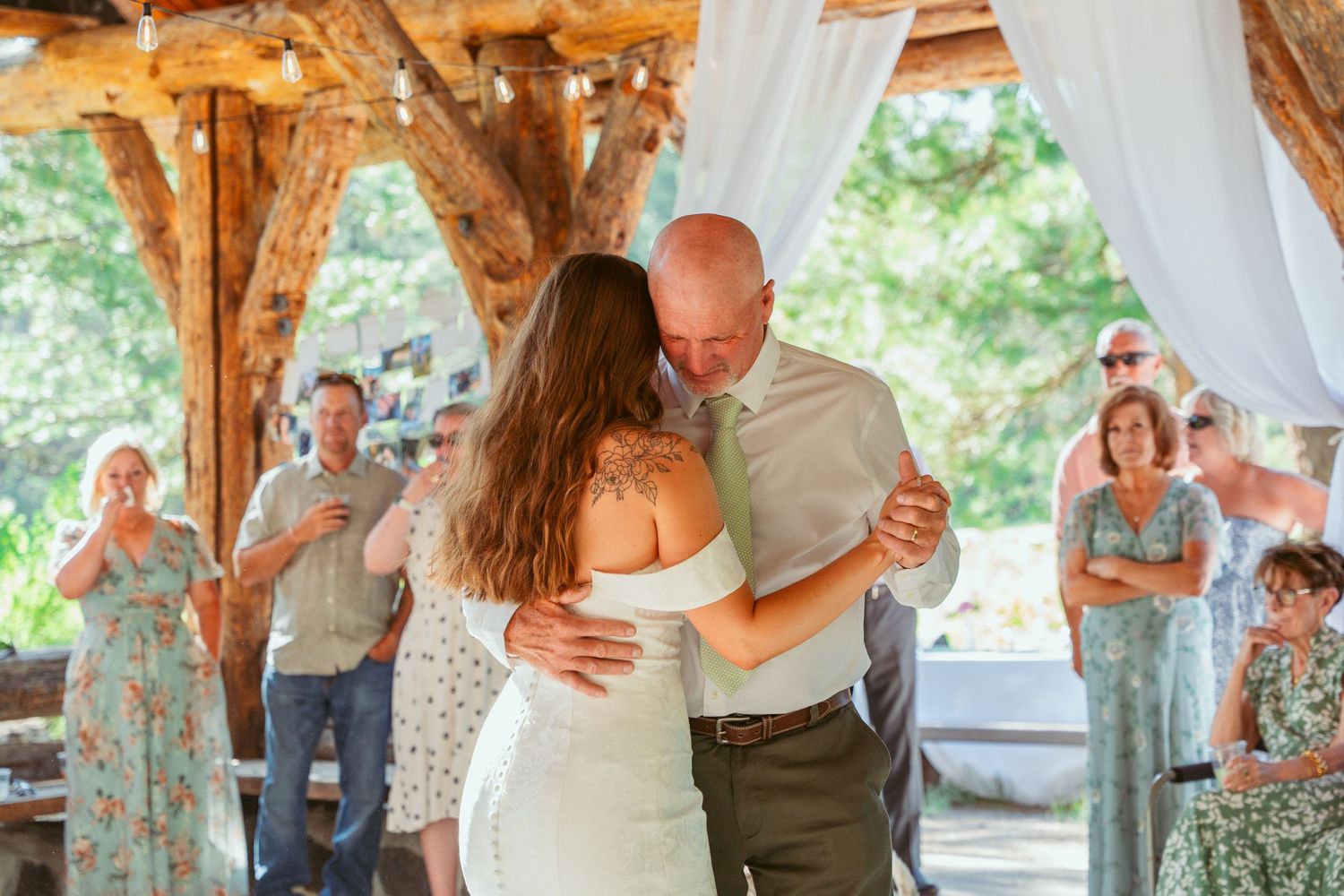 First dance at a wedding reception under a wooden pavilion with natural lighting.
