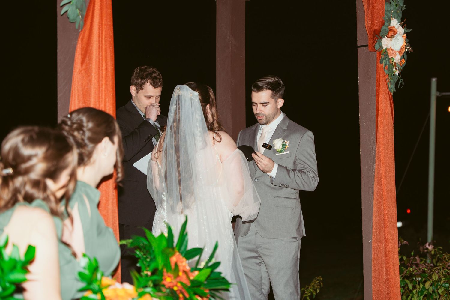 Evening wedding ceremony with orange draped gazebo and floral arrangements.