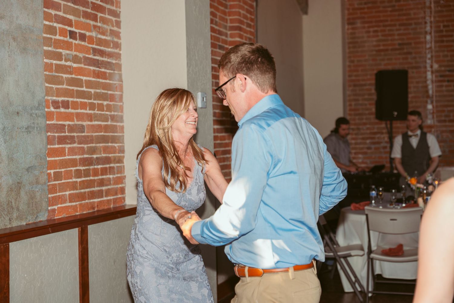 Wedding guests dancing together in a rustic brick venue with warm lighting.