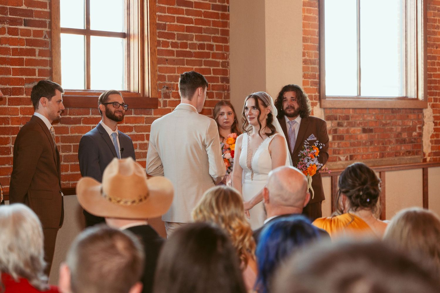 Wedding guests gathered in an industrial-style brick room for a ceremony.