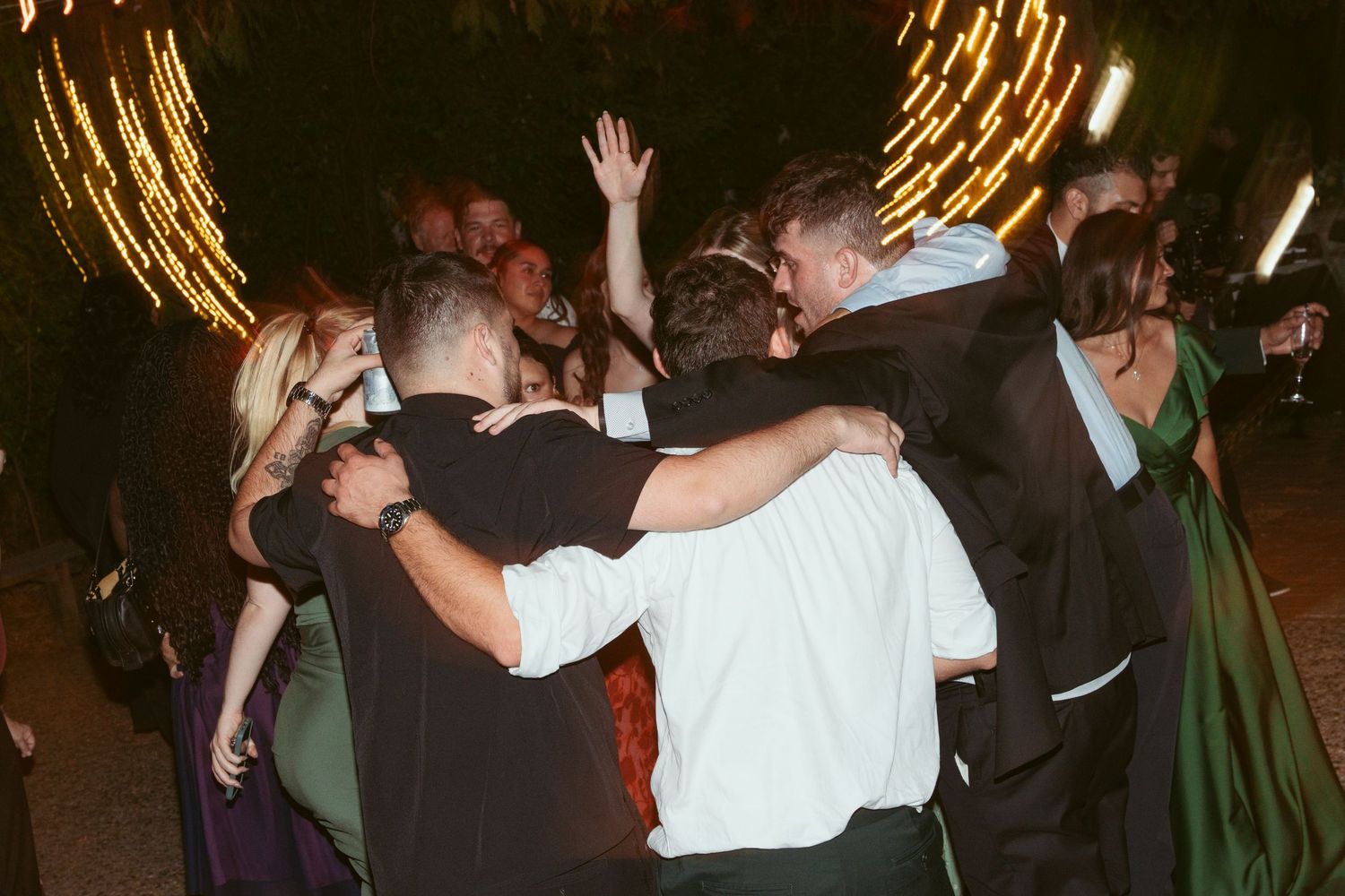 Lively dance floor scene at a nighttime wedding reception with guests celebrating.