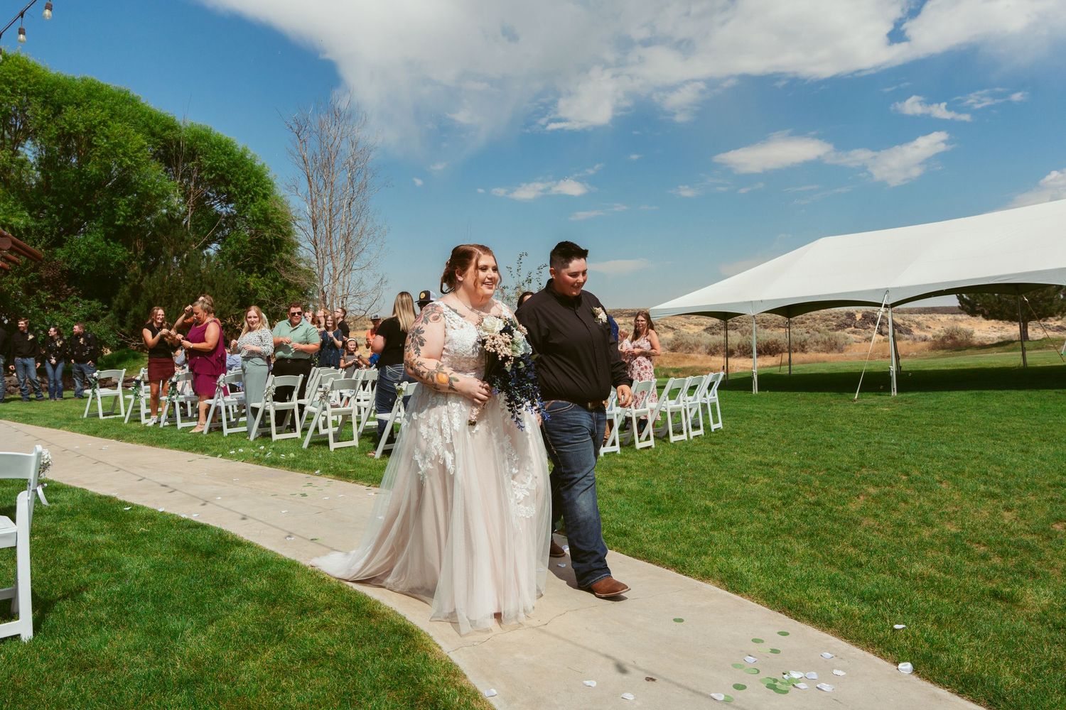 Outdoor wedding ceremony setup with white chairs and scenic mountain views in the background.