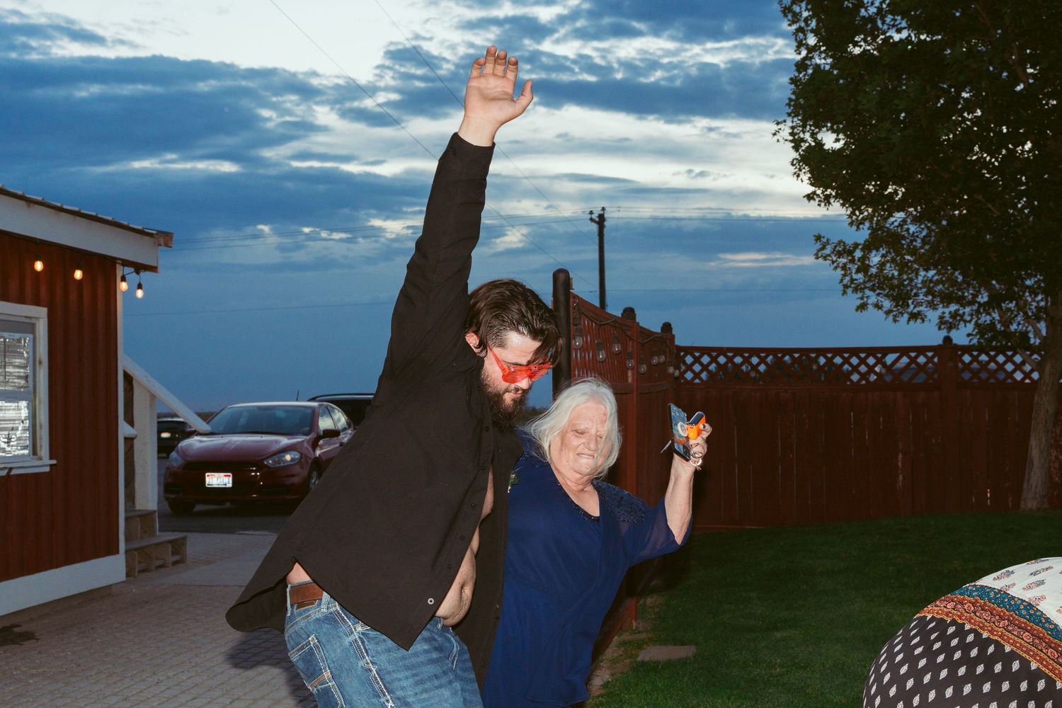 Wedding guests dancing and celebrating with raised arms against evening sky.