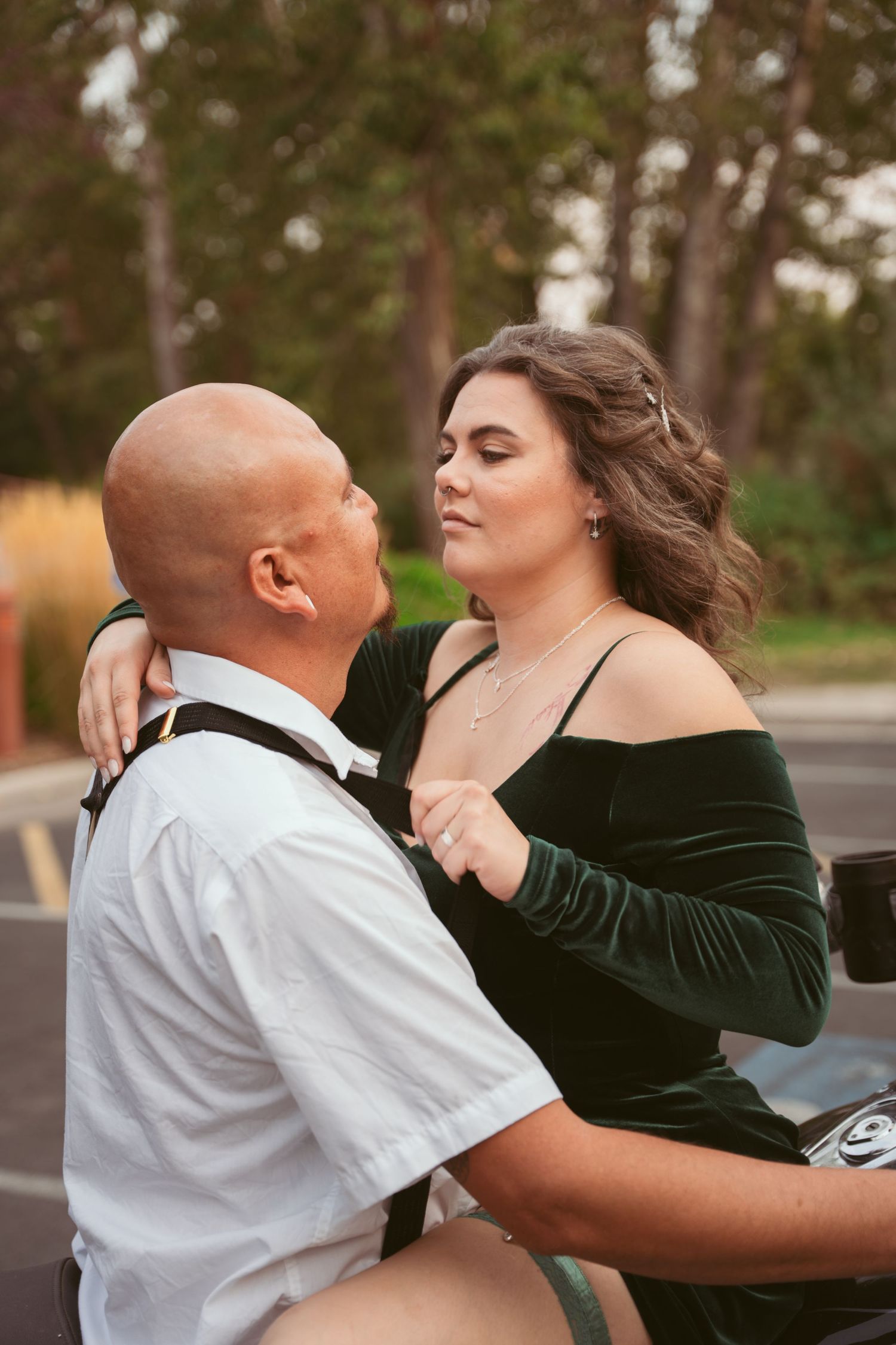 A romantic couple dancing together in a natural outdoor setting with trees in the background.