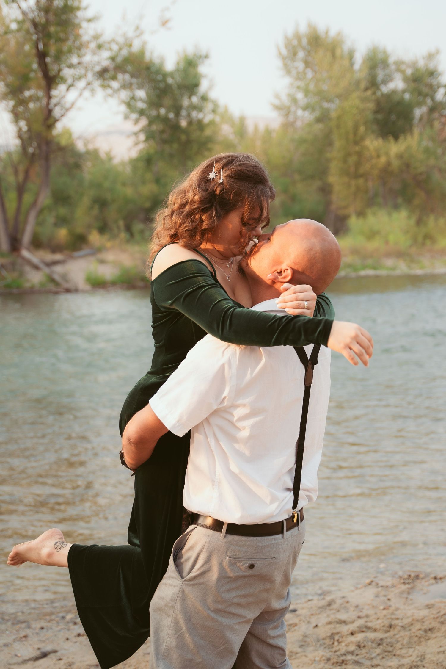 A romantic embrace captured by the water's edge during sunset.