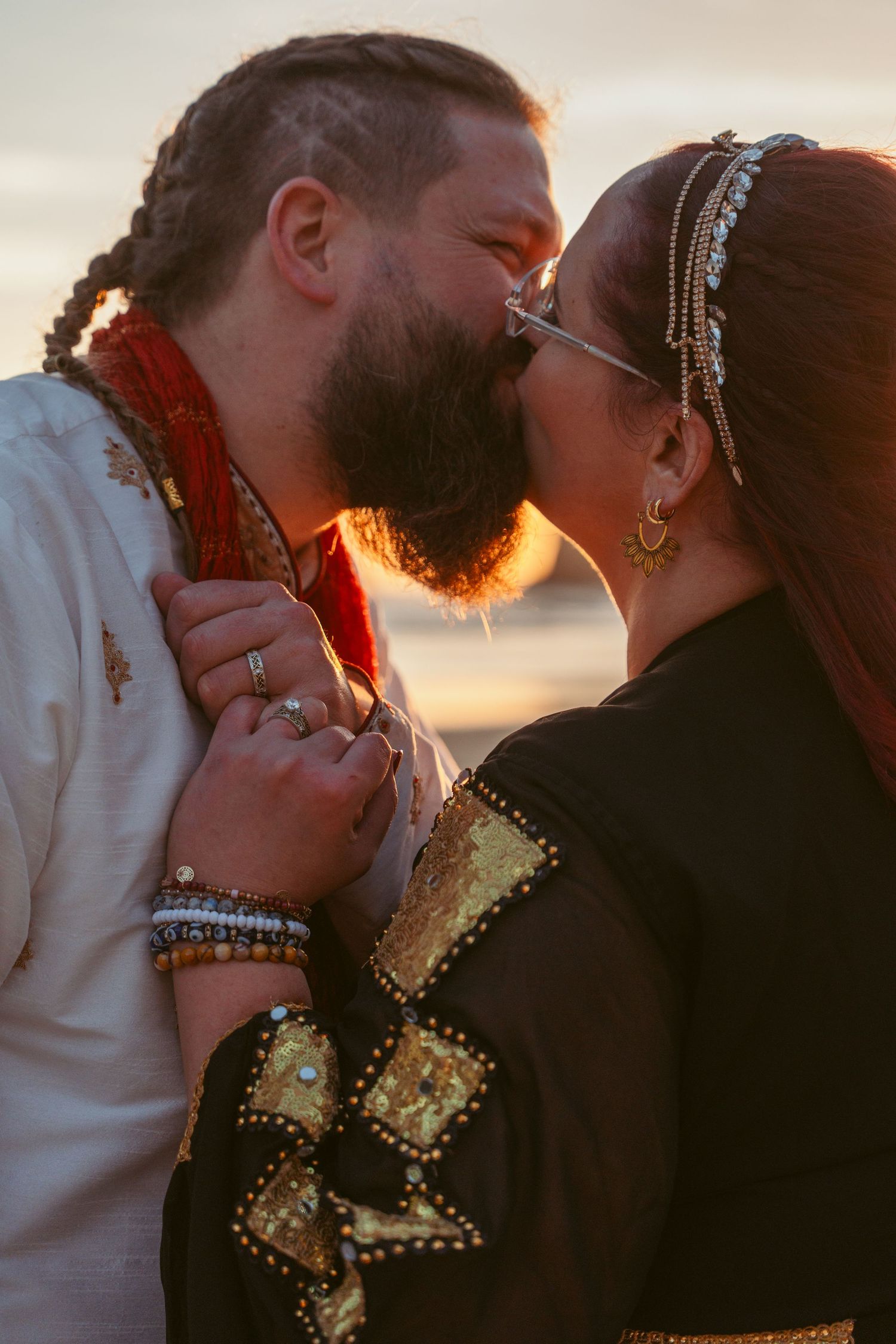 A romantic sunset kiss between a couple in wedding attire with golden light illuminating the scene.