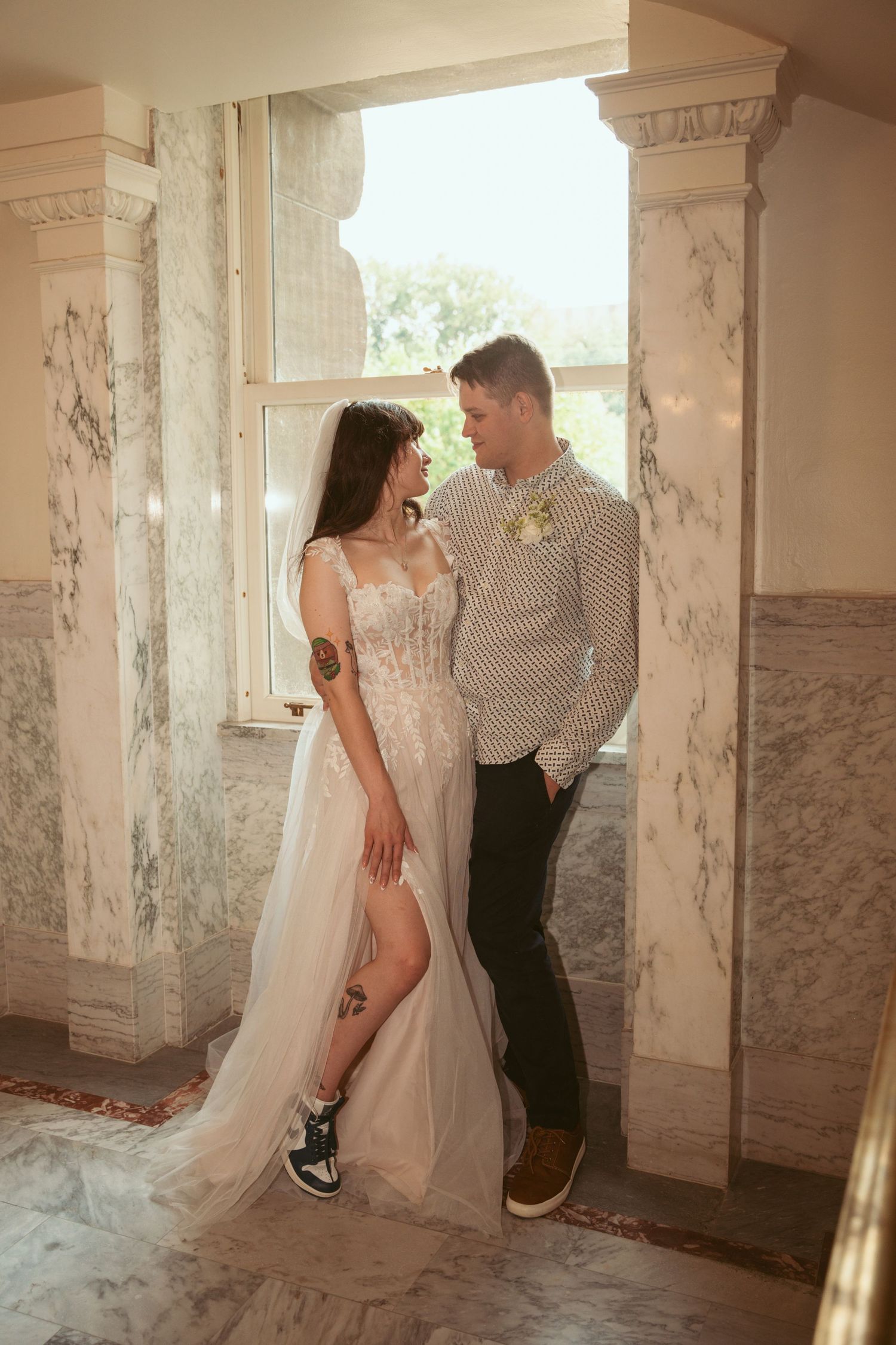 Romantic moment captured in a vintage indoor setting with marble columns and natural lighting.