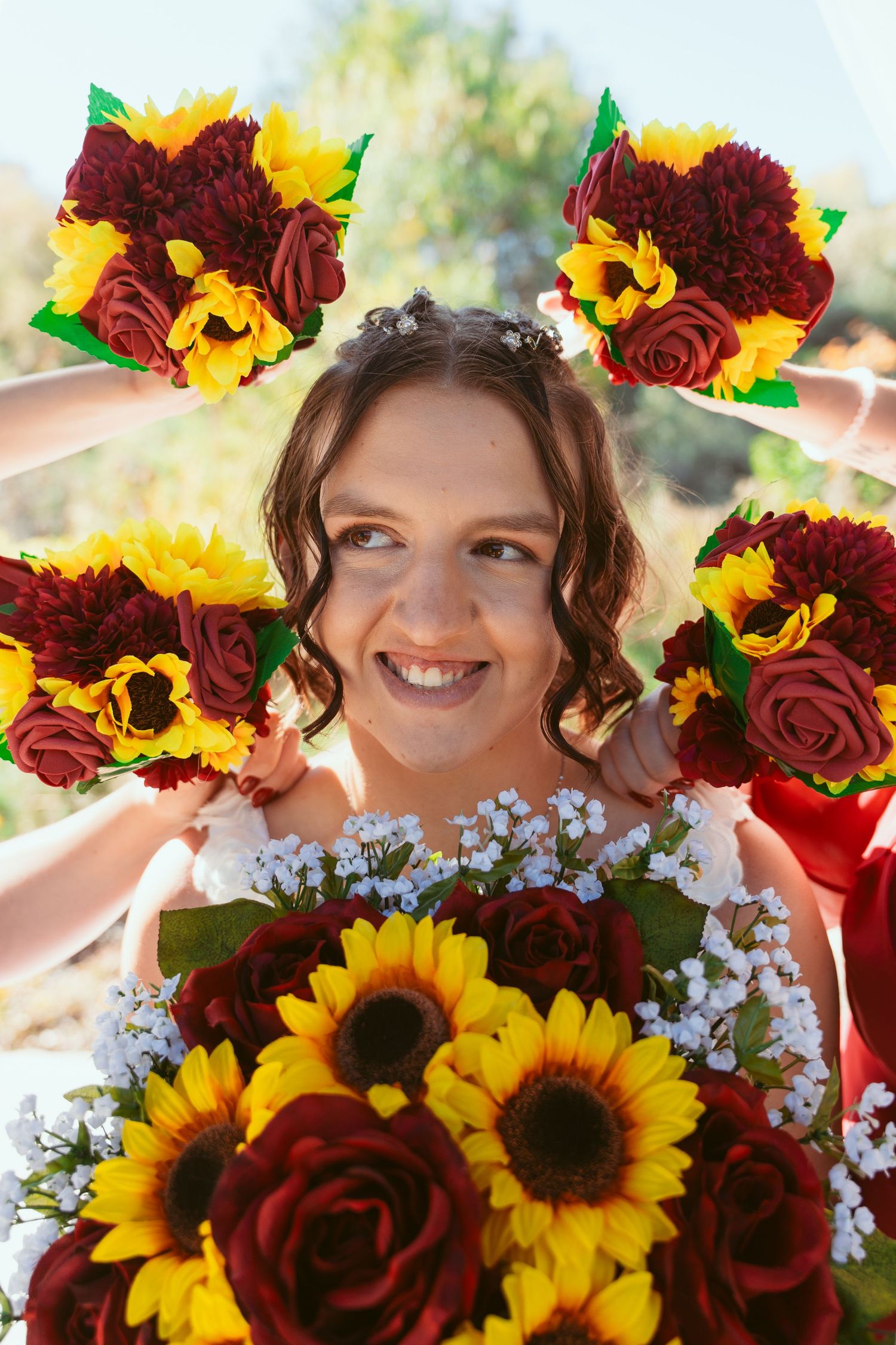 Joyful portrait with sunflower and rose floral crown against sunny outdoor setting.