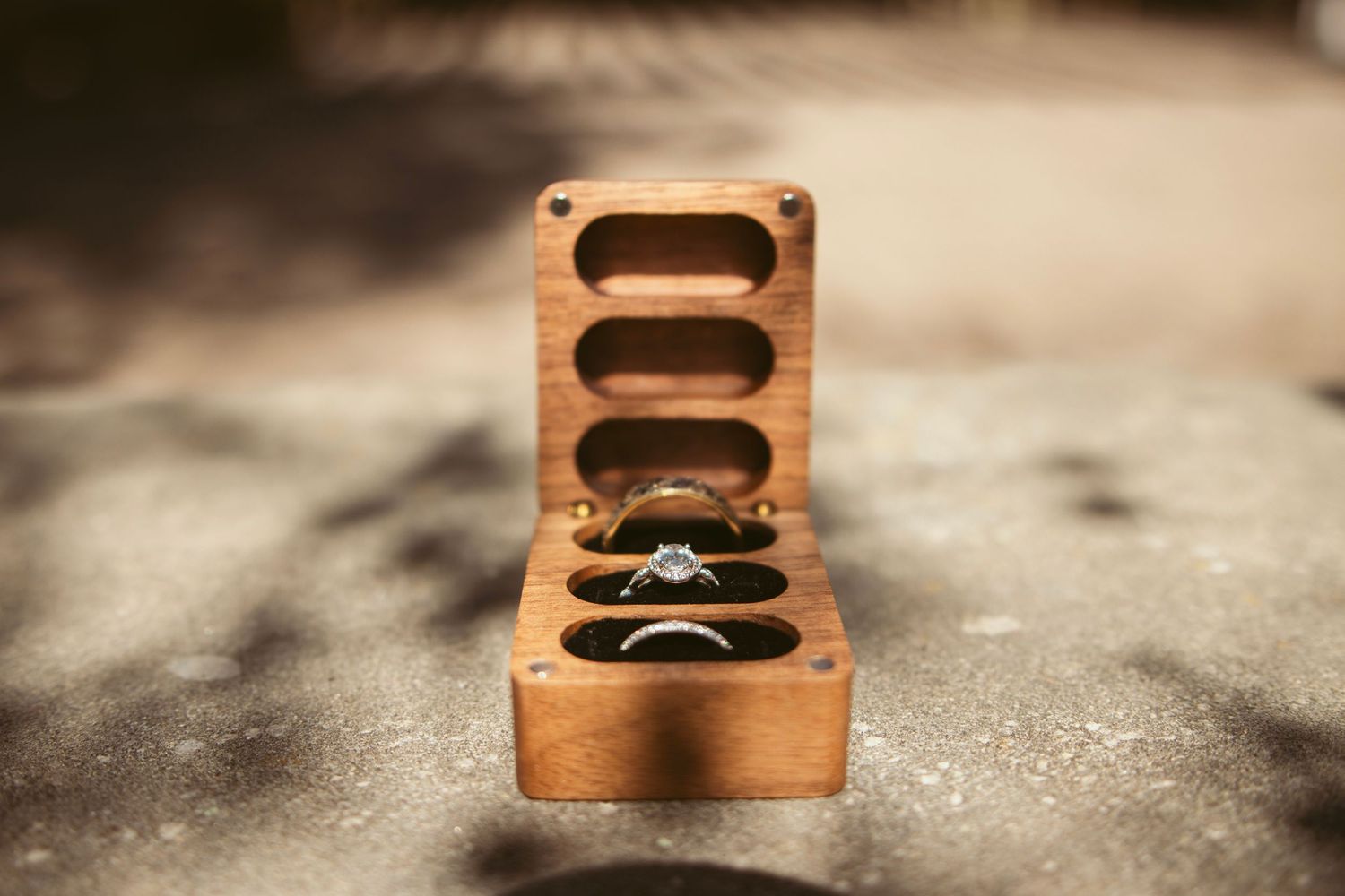 Wooden ring box with vintage styling on textured surface.