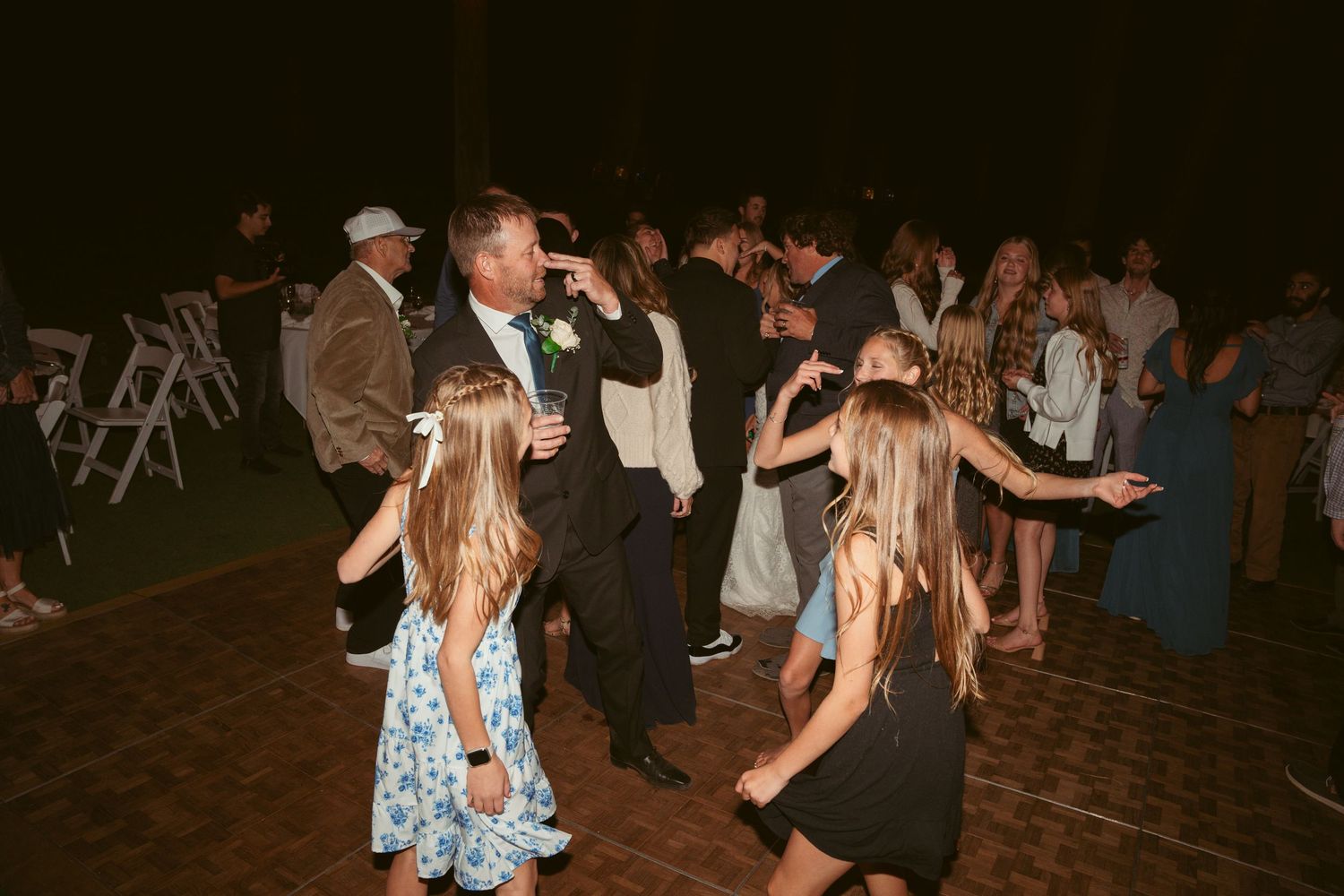 Lively dance party at an outdoor wedding reception with guests enjoying the music.