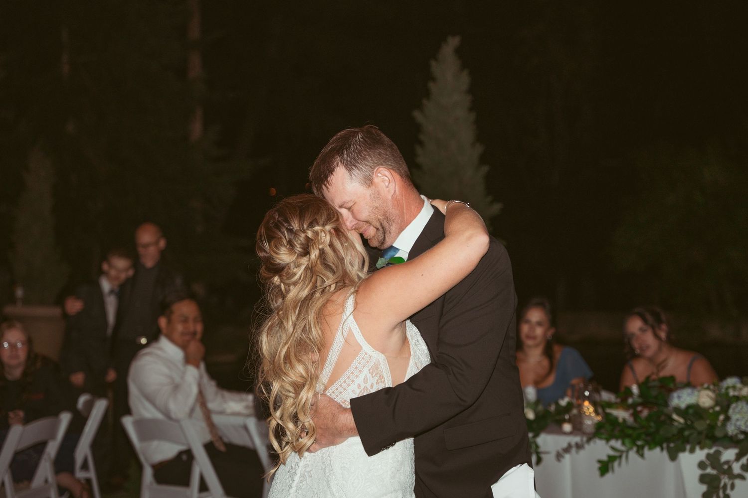 Couples dancing together during a romantic moment at an outdoor evening wedding celebration.
