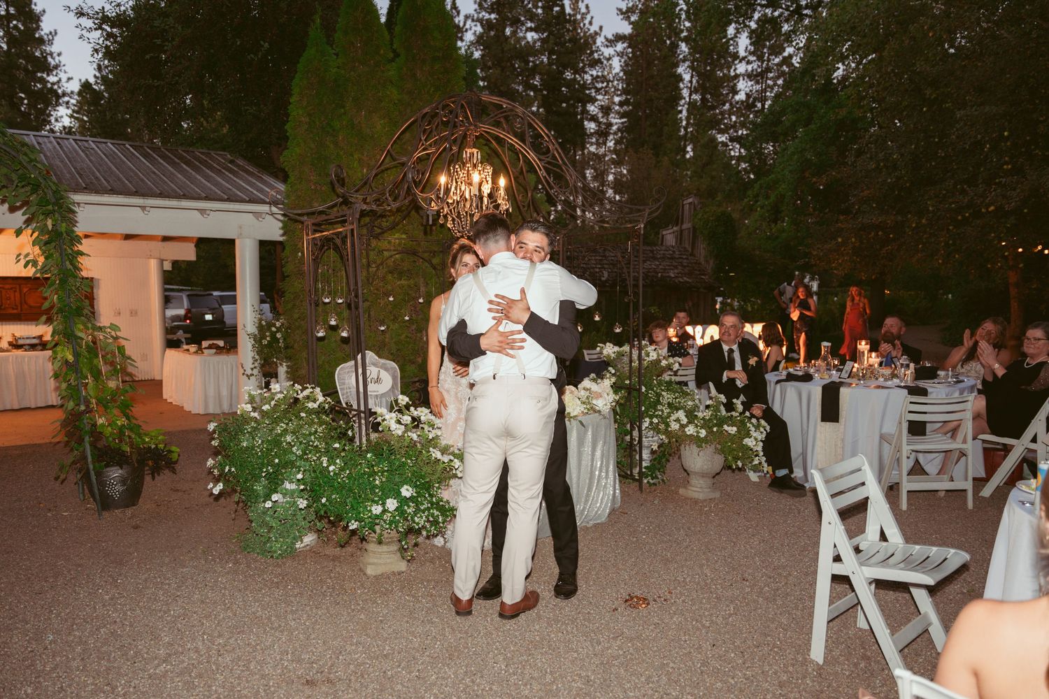 Couple sharing their first dance at an outdoor evening wedding reception with string lights.