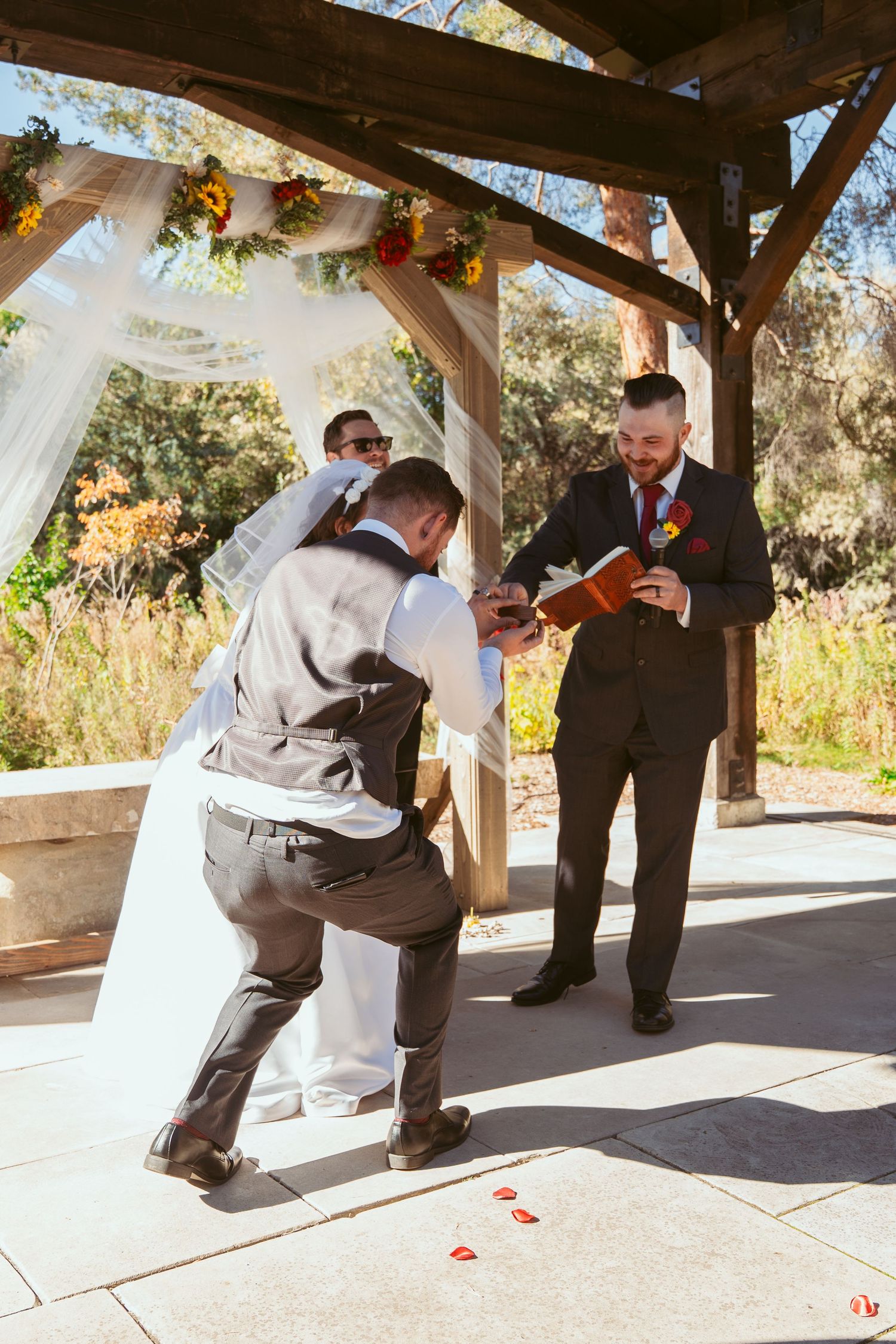 Wedding ceremony moment showing someone kneeling on the ground during an outdoor autumn service.