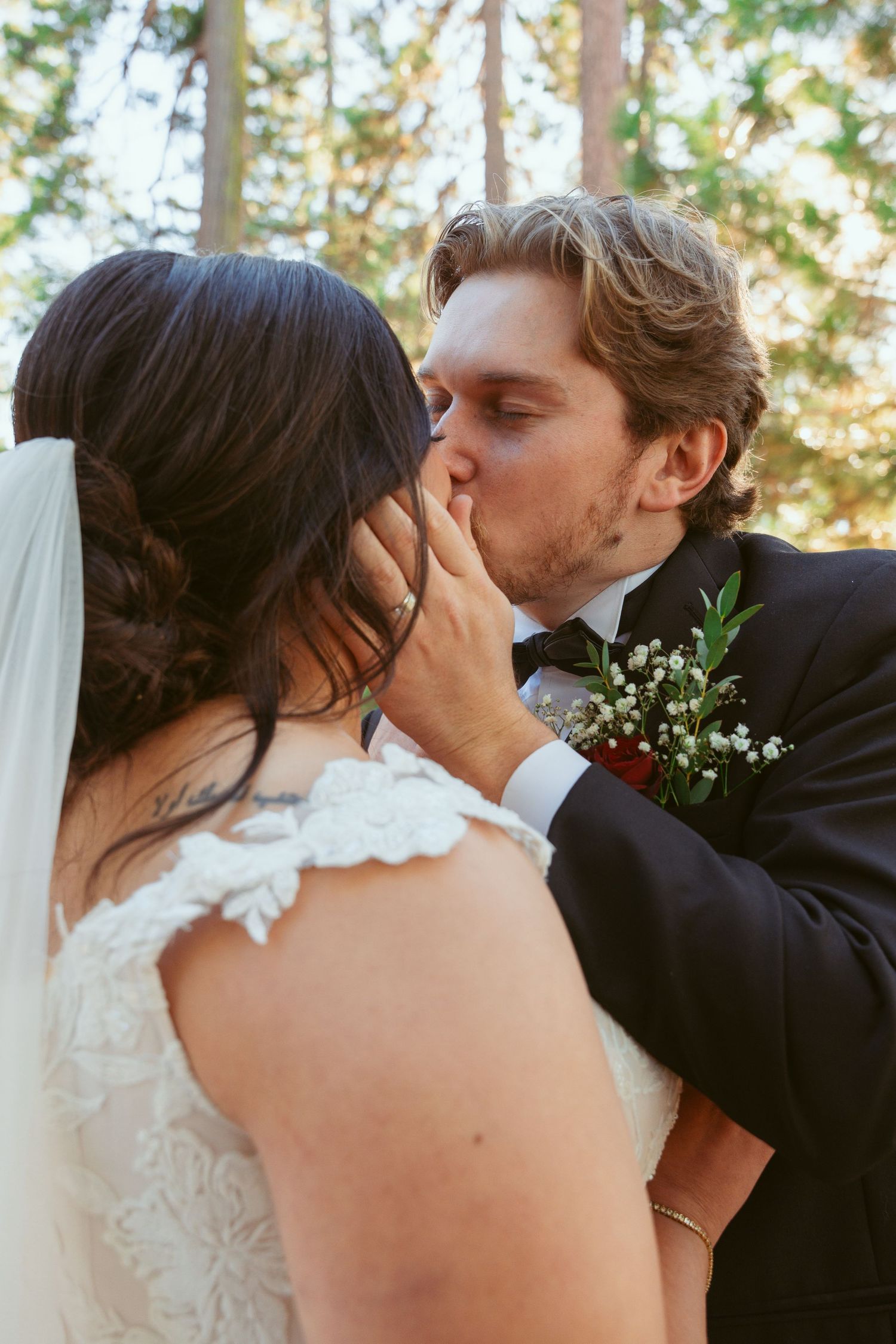 Intimate close-up of a tender wedding kiss amidst a forest backdrop.