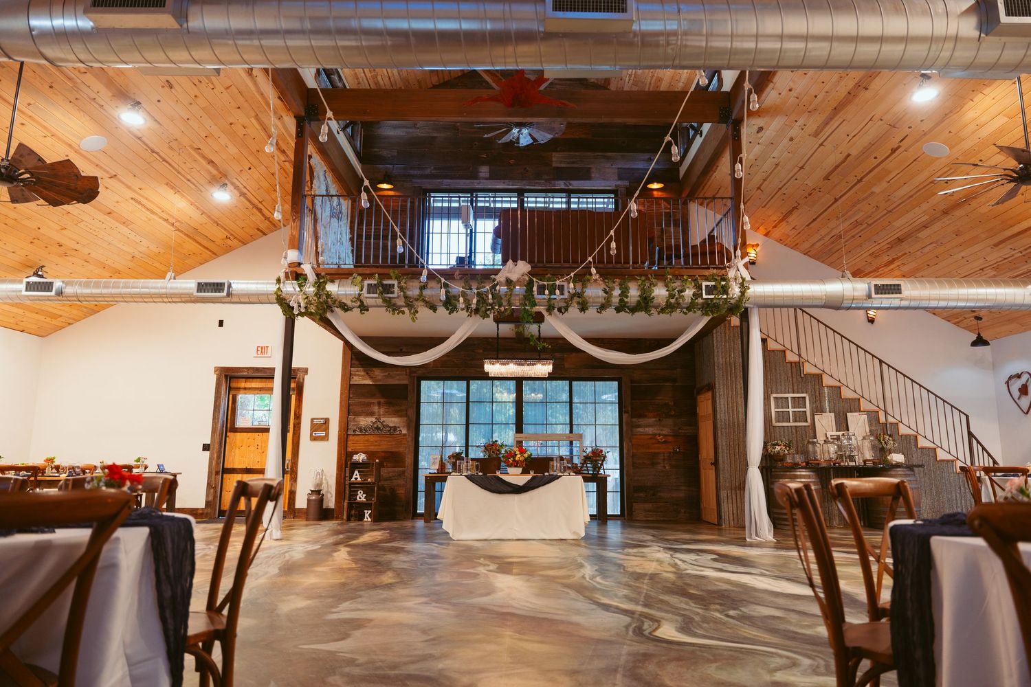 Indoor wedding ceremony space with wooden floors and decorative balcony.