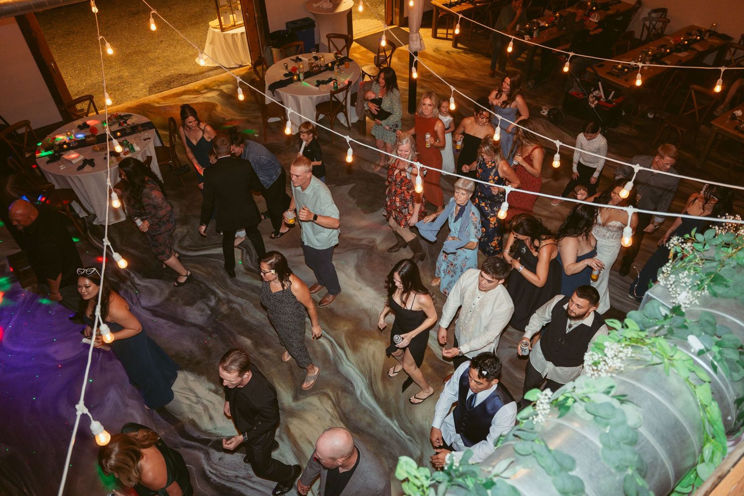 Festive wedding reception scene with string lights and dancing guests.