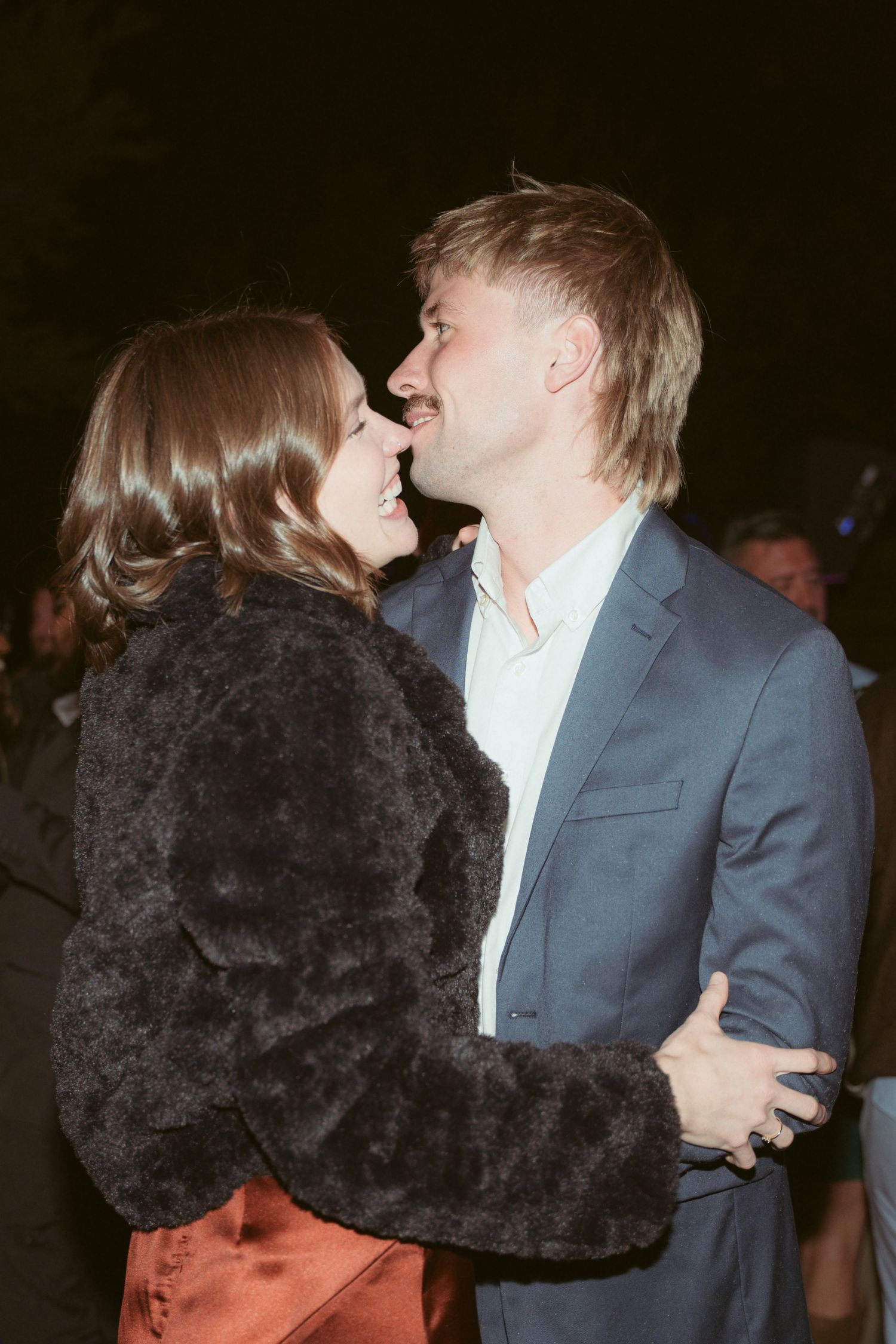 Couple in formal attire sharing an intimate dance moment at a nighttime event.