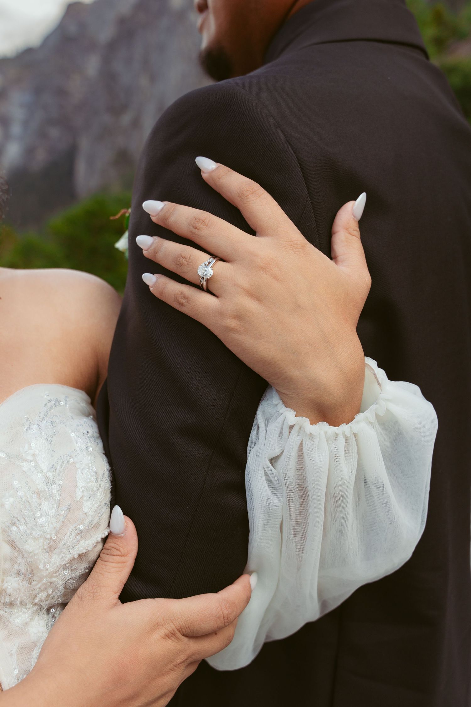 Detail shots of hands embracing during a wedding photoshoot with lace sleeve details.