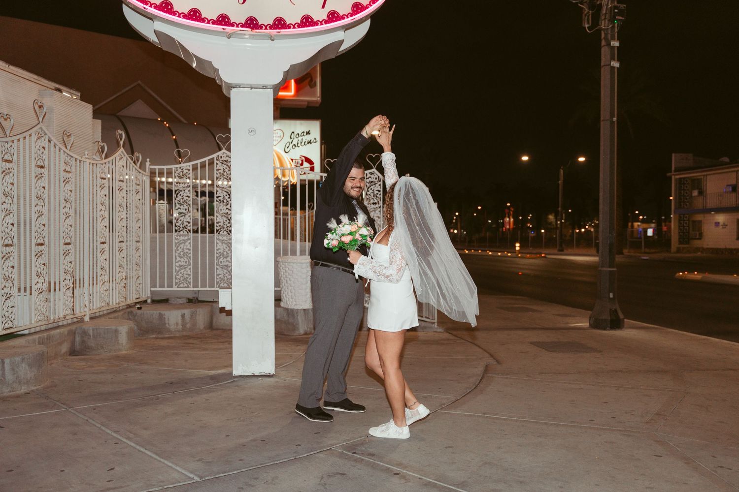 Nighttime view of a couple dancing under illuminated columns at an outdoor venue.